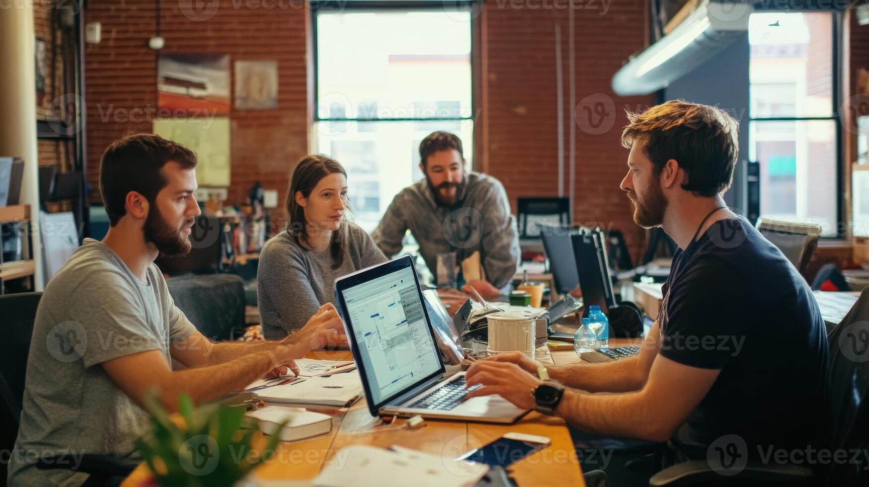 A collaborative team working on projects with computers and papers photo