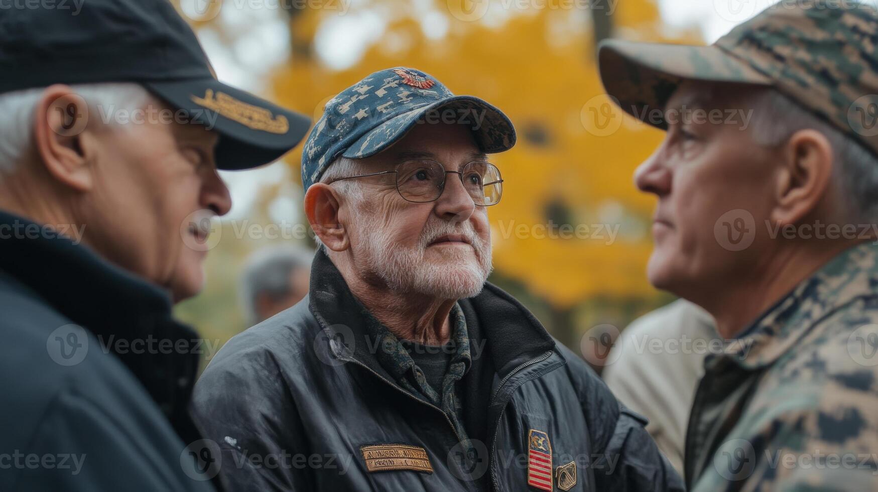 Three older veterans wearing hats engage in outdoor conversation together photo