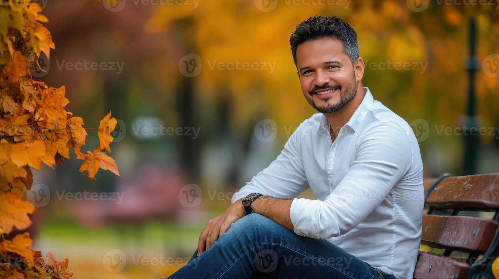Man smiling in autumn park sitting on bench photo