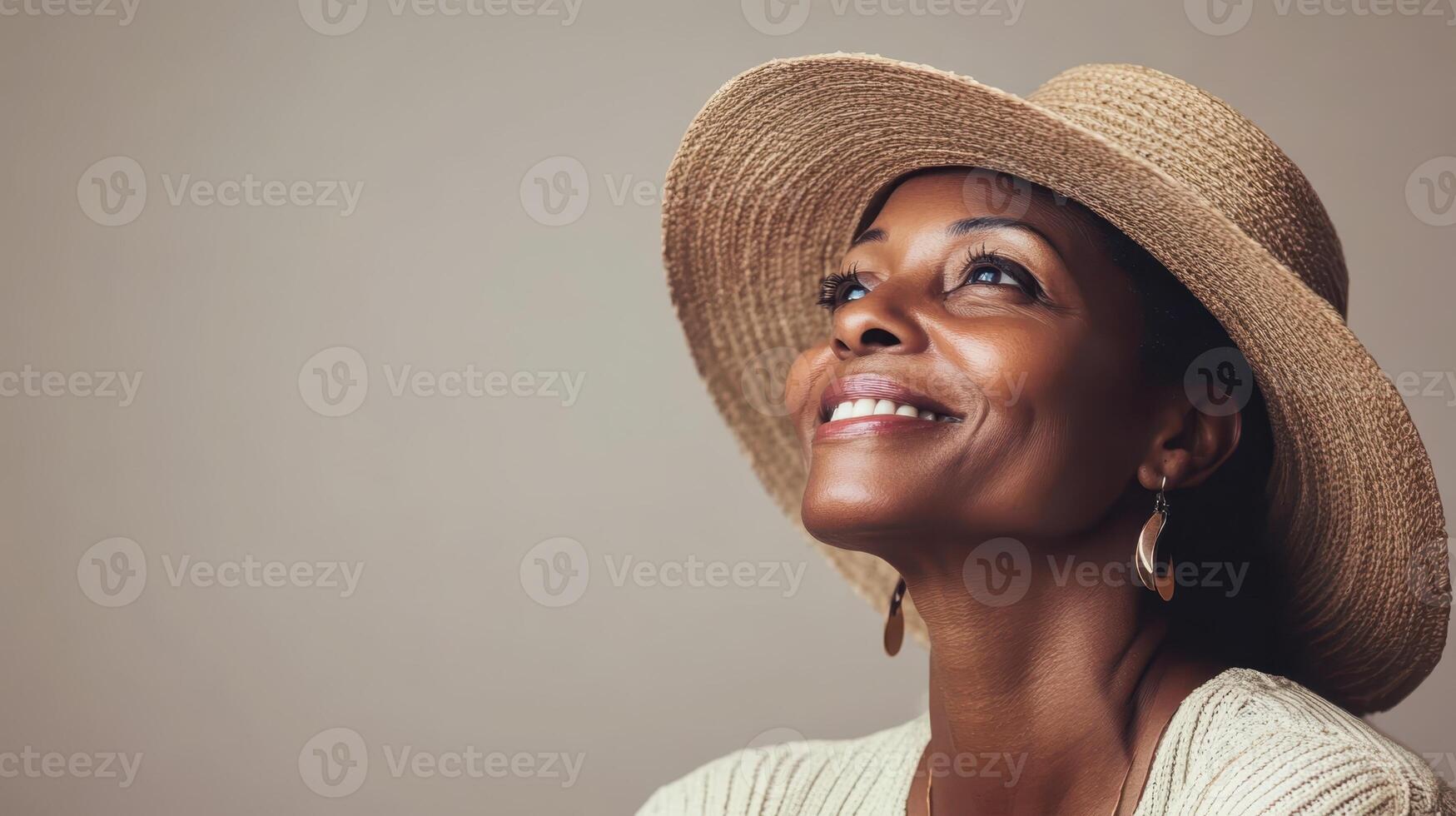 Elegant Woman with Straw Hat Smiling and Looking Upward with Joyful Expression on Beige Background photo