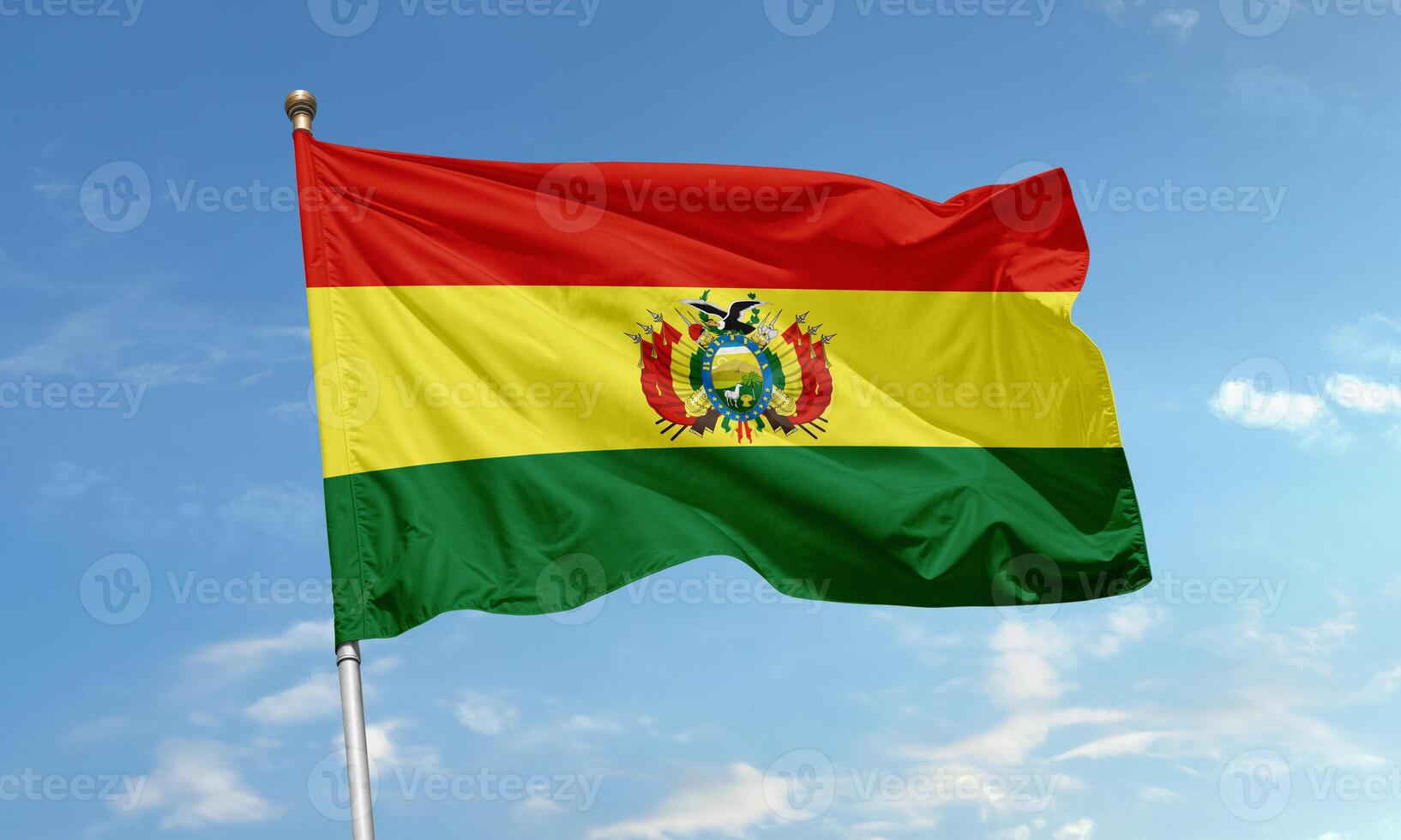 Bolivia national flag with red, yellow, and green horizontal stripes and detailed coat of arms waving in the sky photo