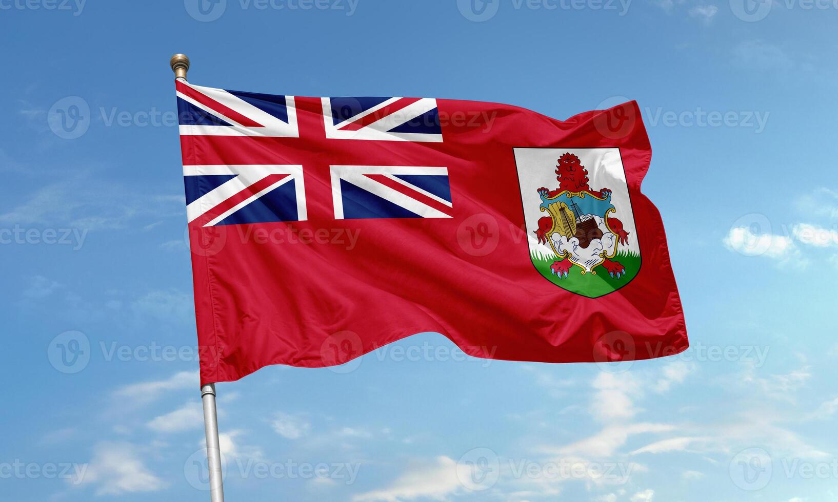Bermuda national flag with Union Jack and coat of arms featuring a lion and ship on a red field flying in the sky photo