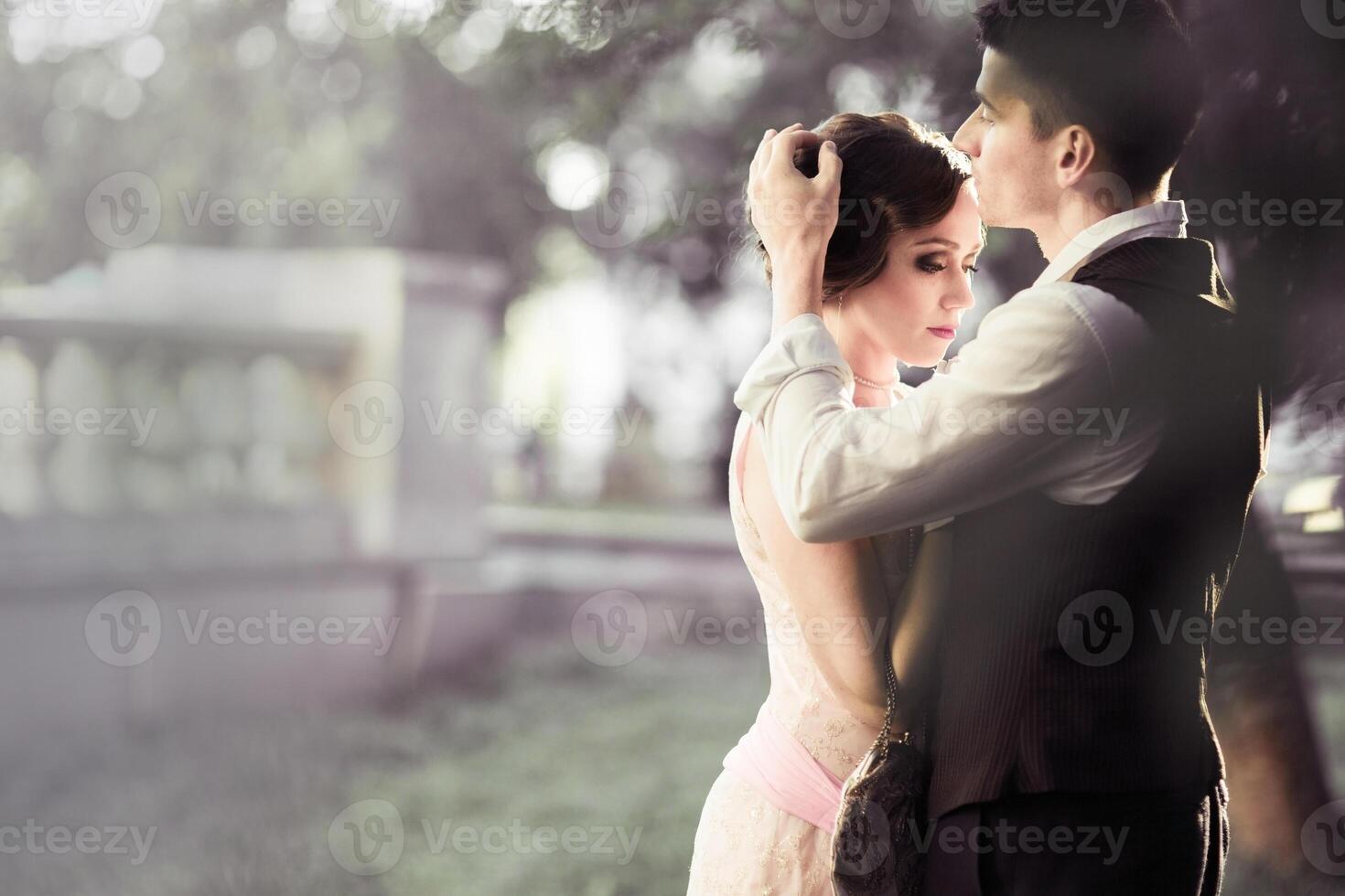 Couple man and woman in retro dress against trees and a fence. Historical 1930s photo