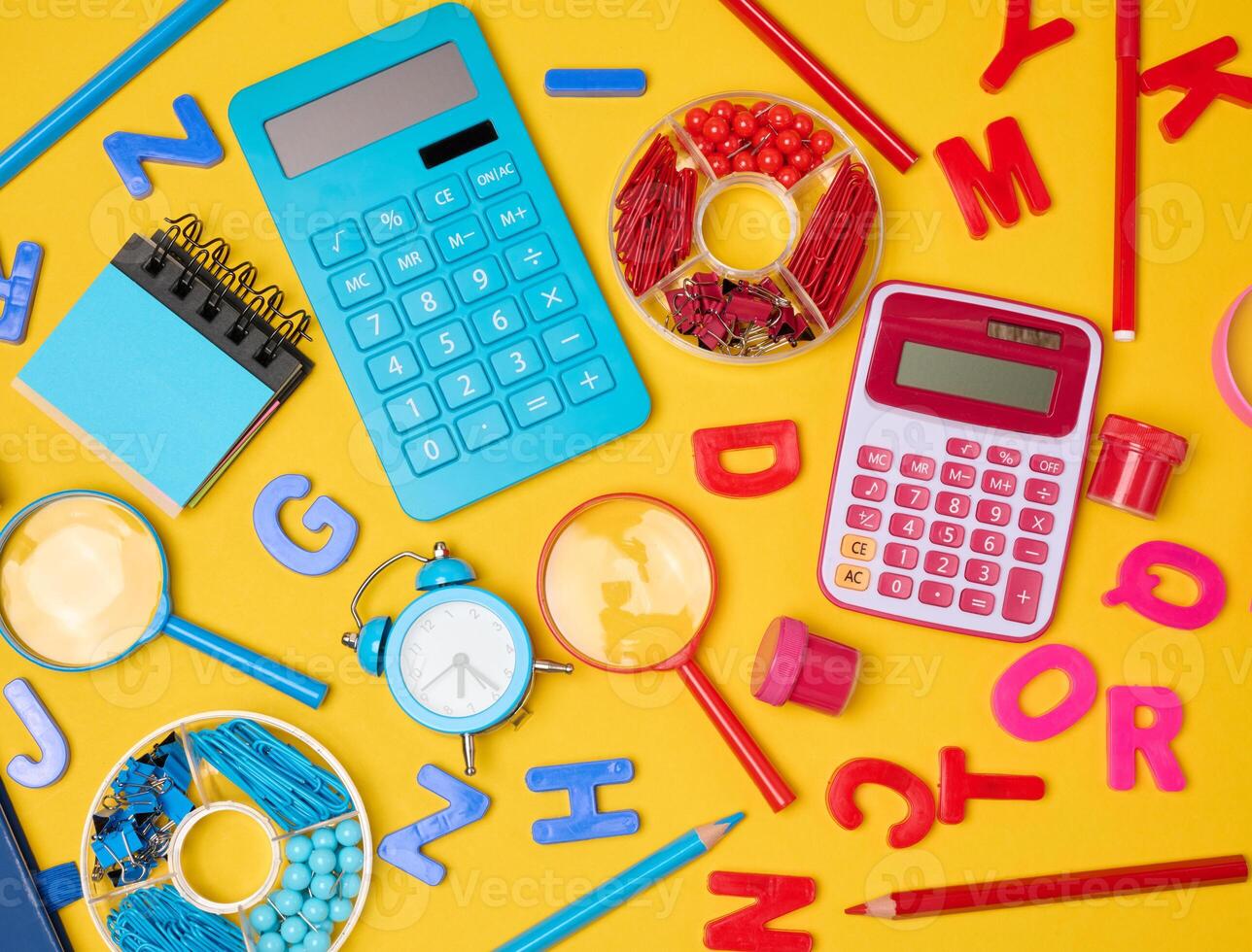 School supplies, learning items calculators, letters, tools, and stationery scattered on a vibrant yellow background. photo