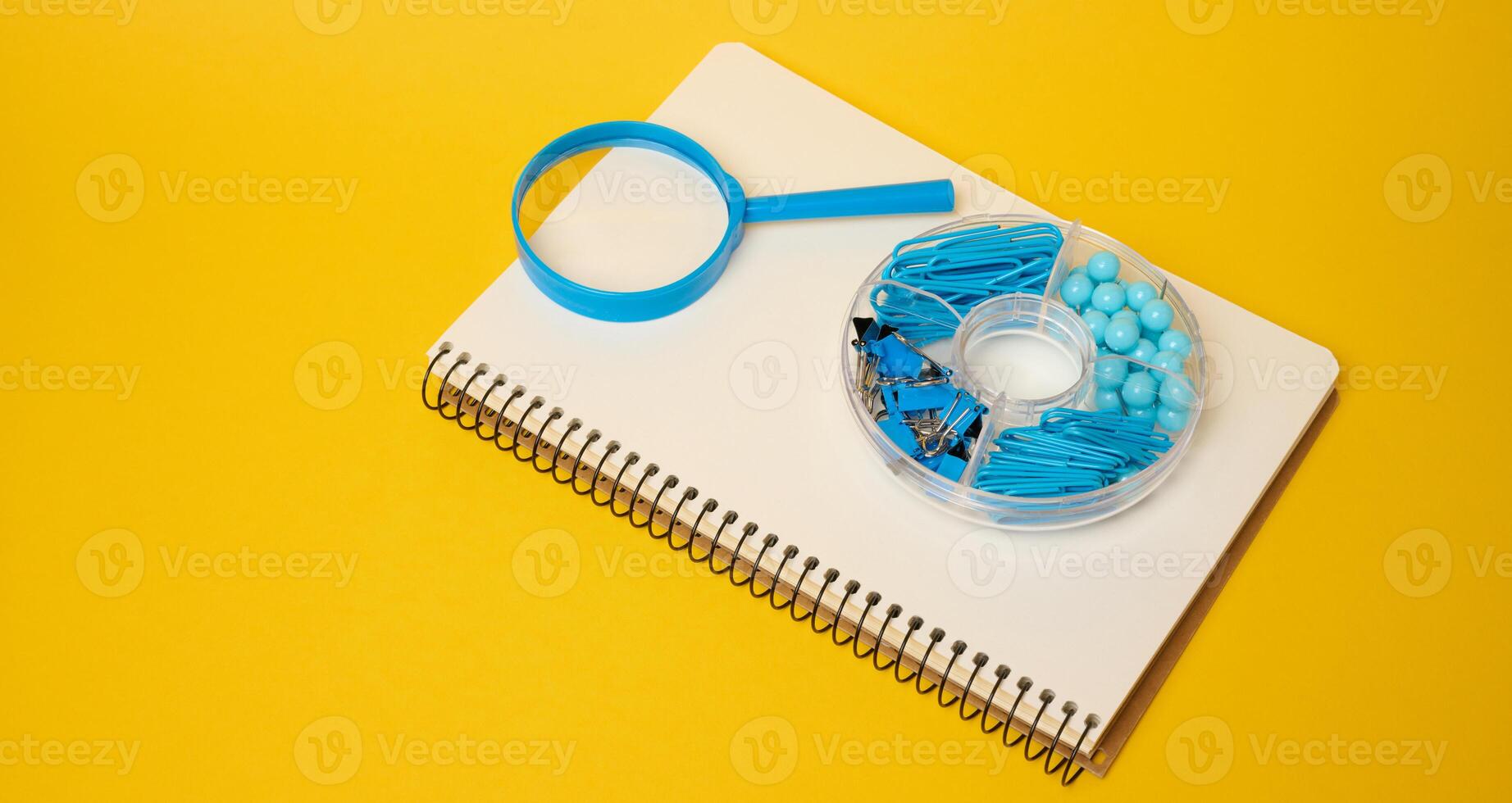 White notebook with blue magnifying glass and blue stationery in organizer symbolizing studying photo