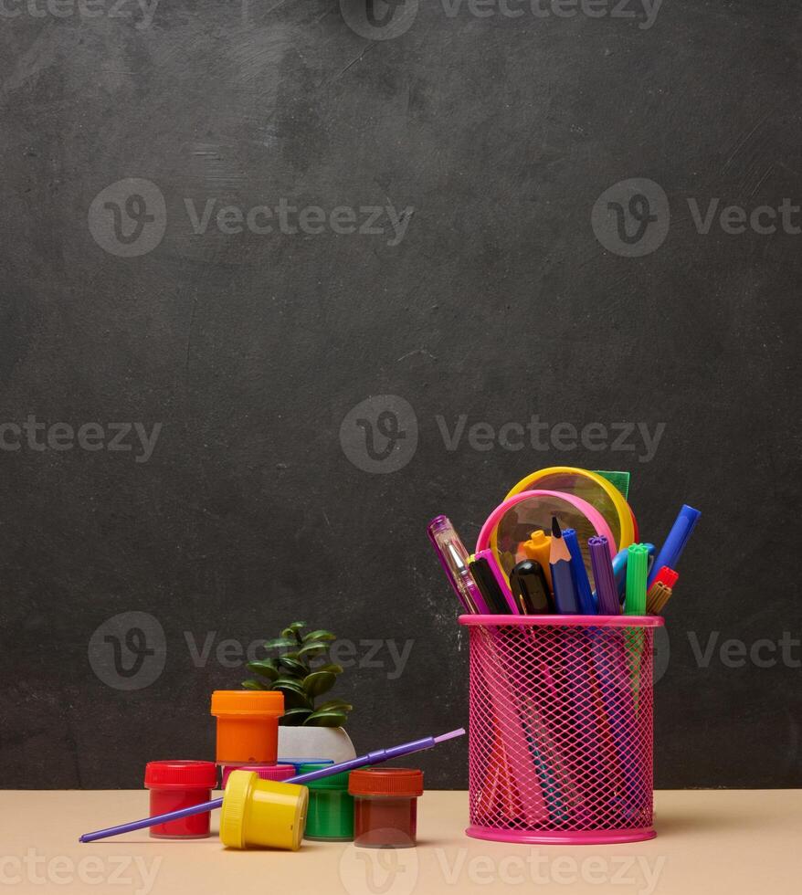 Pink glass with writing utensils, paint cans, brush, creativity or school activities photo