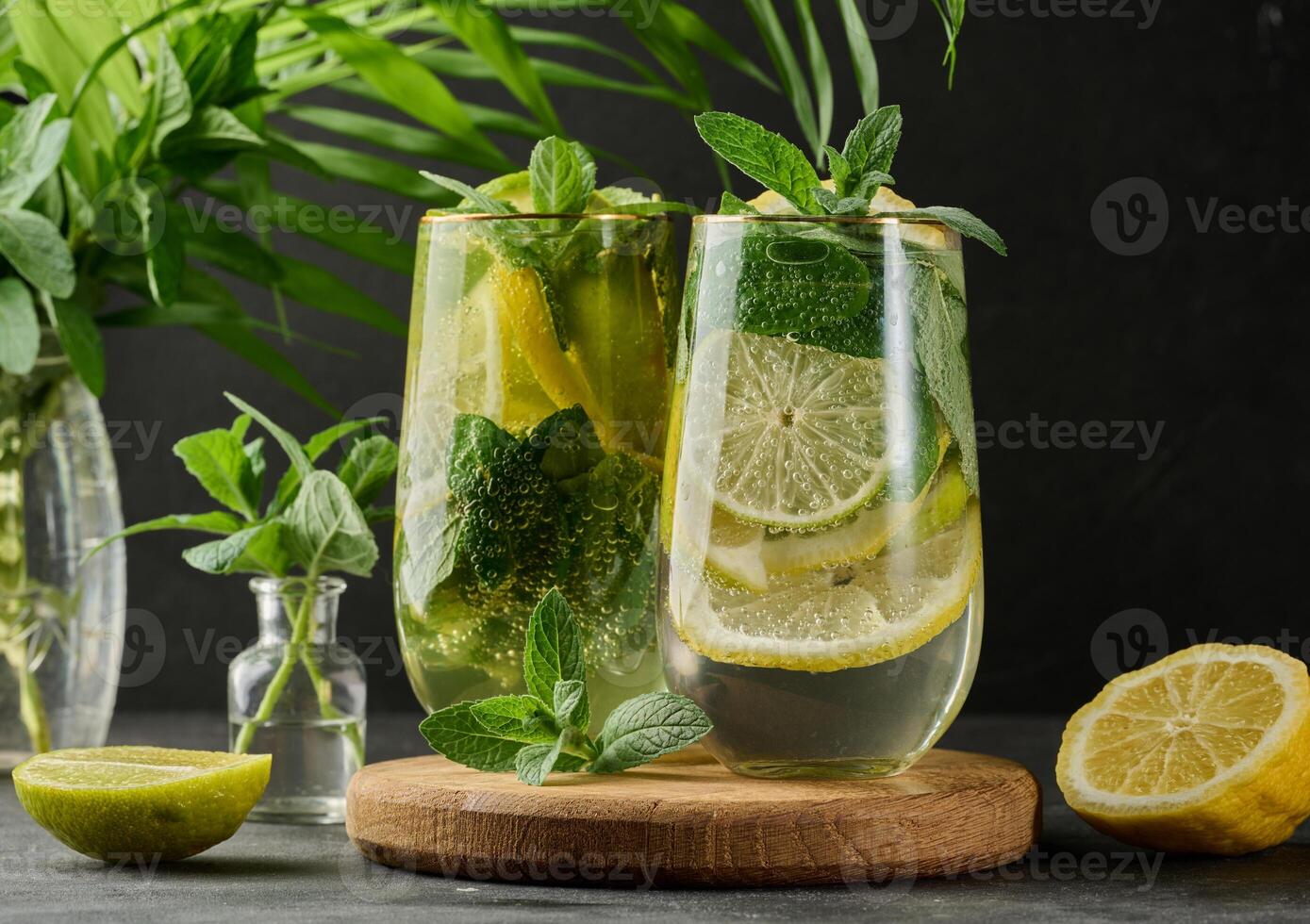 Summer drink in a glass with lemon, lime, mint, ice, and metal straw. Dark background photo