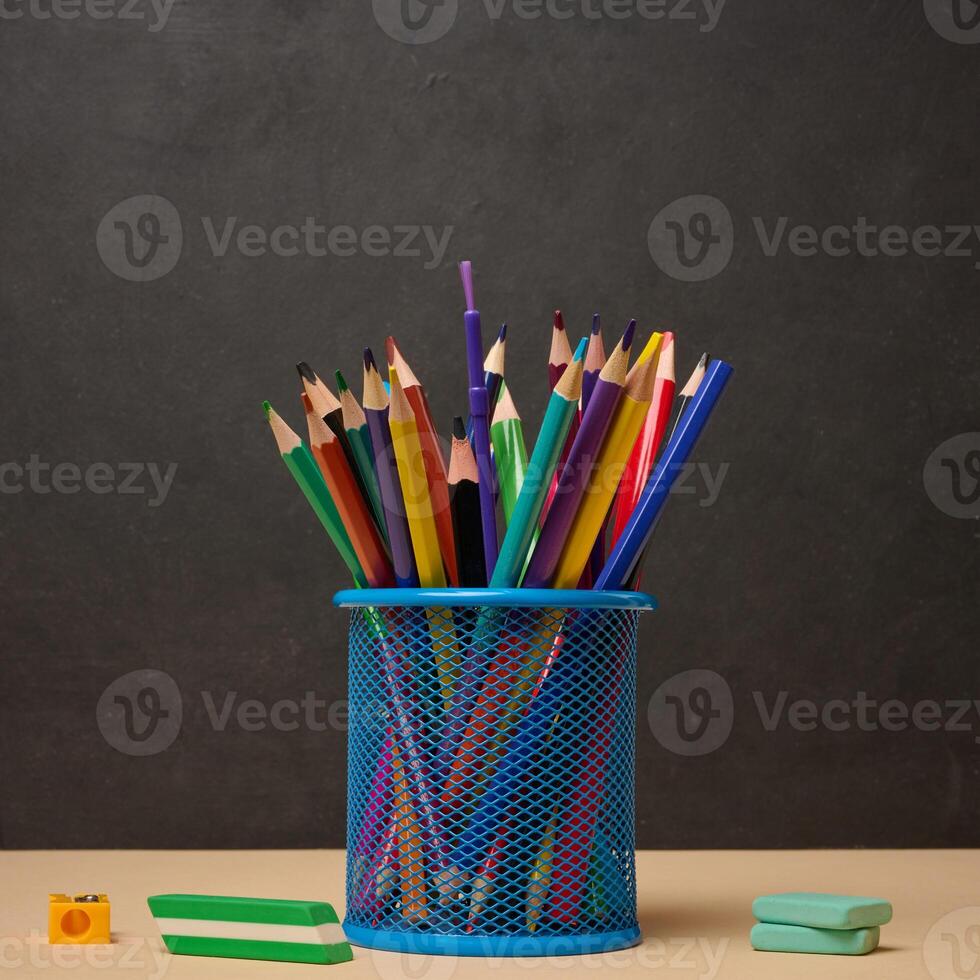 Multi-colored pencils in a blue metal cup, sharpener and erasers symbolizing study or creativity photo