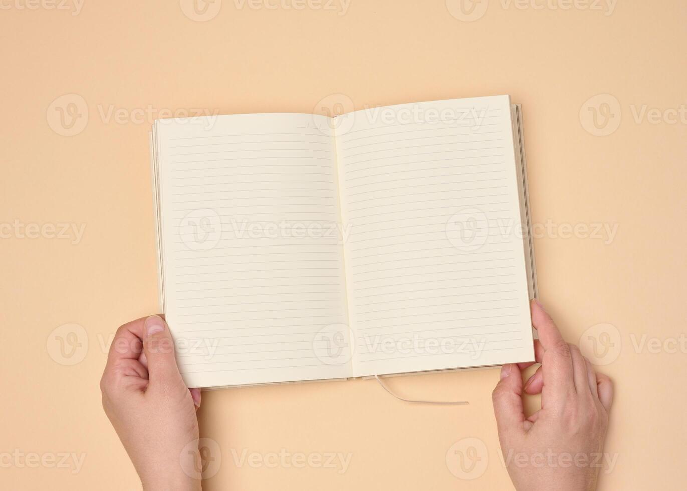 Hands hold a blank open notebook on a neutral background photo