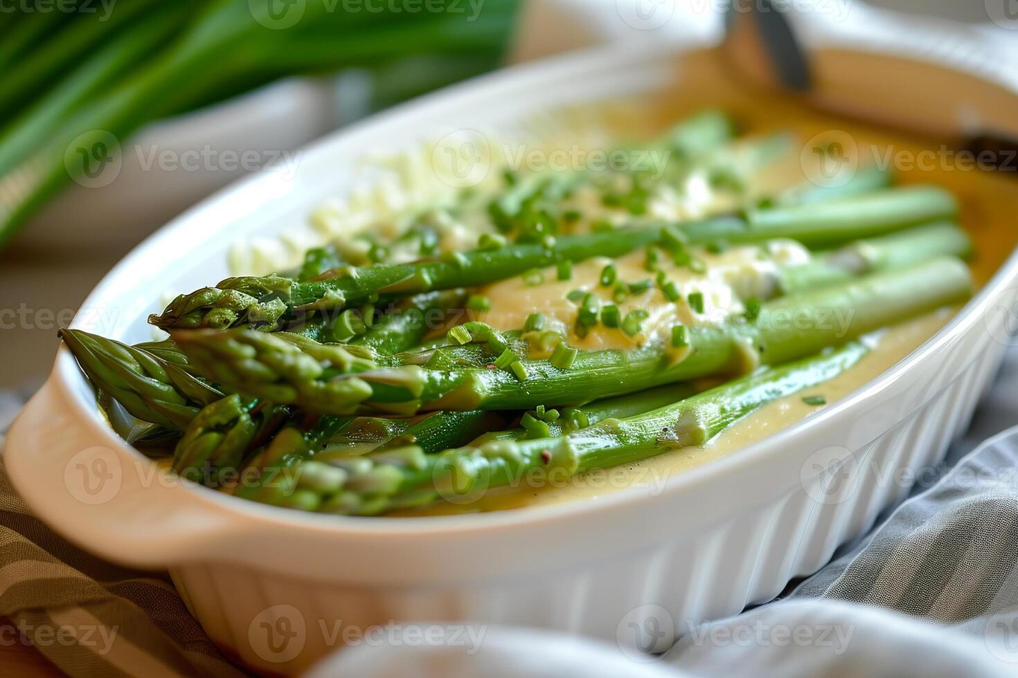 Oven baked asparagus with cheese and chives in white dish. photo