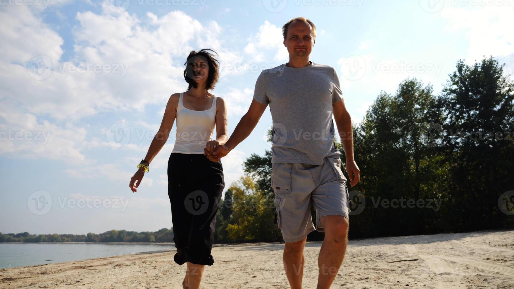Romantic couple holding hands of each other and jogging at coastal. Happy pair running along seashore at sunny day. Lovers spending time together at resort. Concept of summer vacation or holiday photo