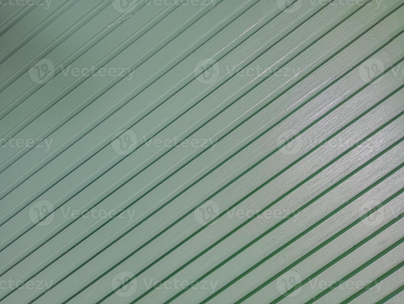 Diagonal Green Wooden Panel Texture. A close-up view of diagonally arranged green-painted wooden slats with a glossy surface. photo
