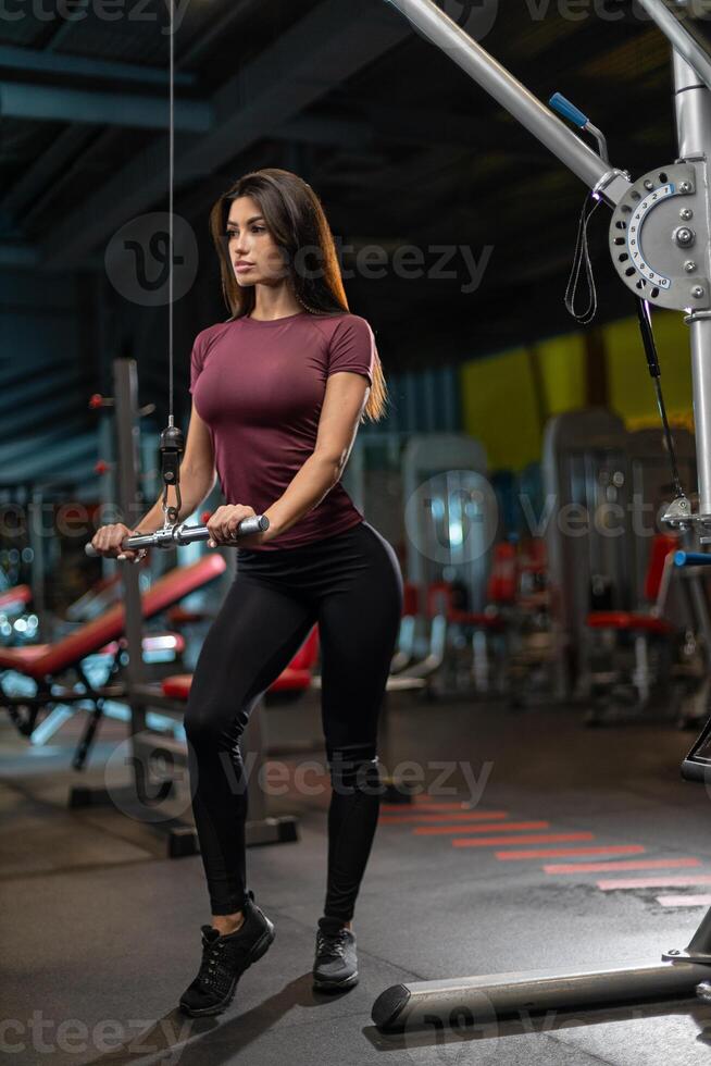 Strong woman exercising in gym using cable machine for fitness workout routine in modern training facility photo