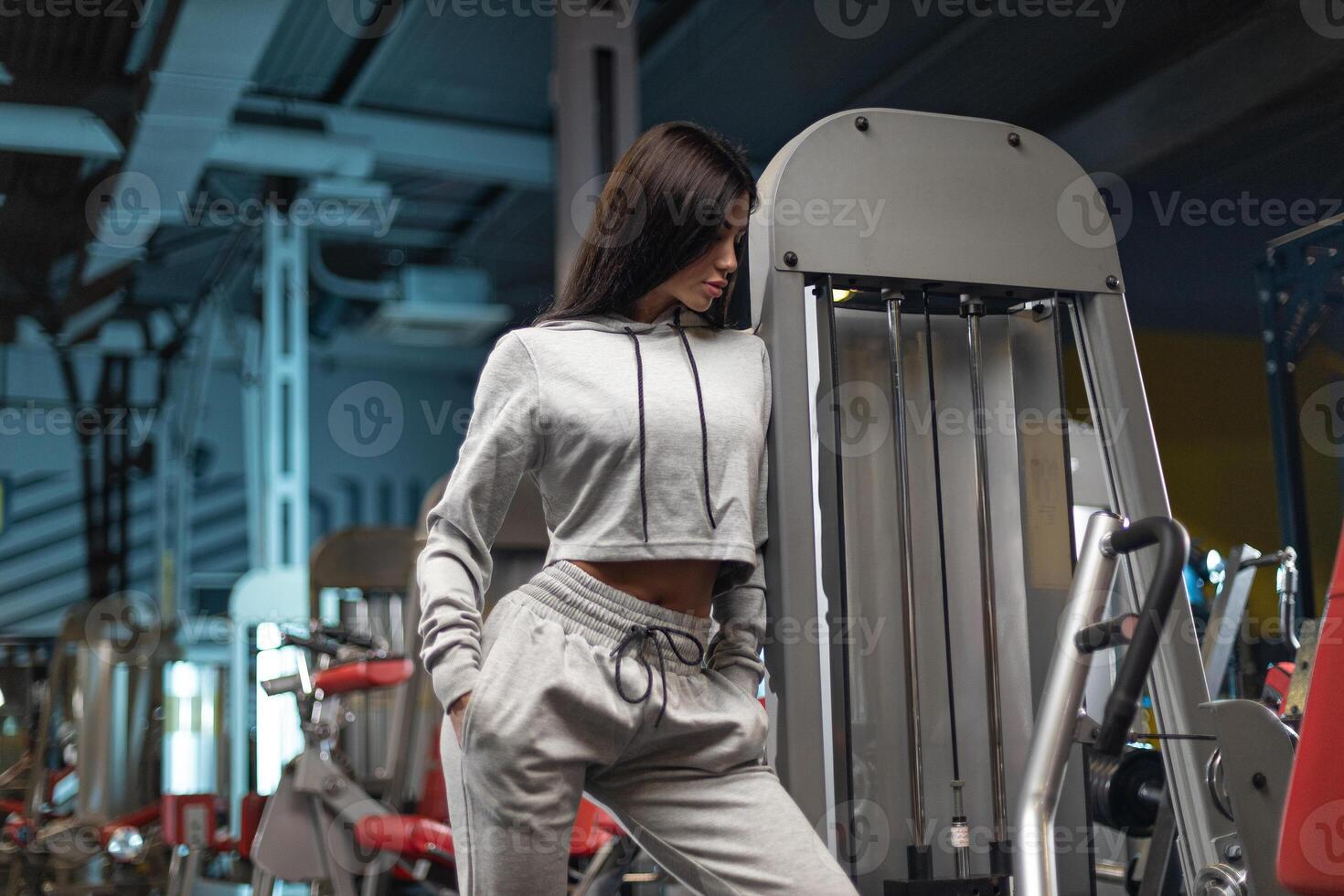 Fitness enthusiast dressed in comfortable athletic wear interacts with gym equipment during workout session in modern gym photo