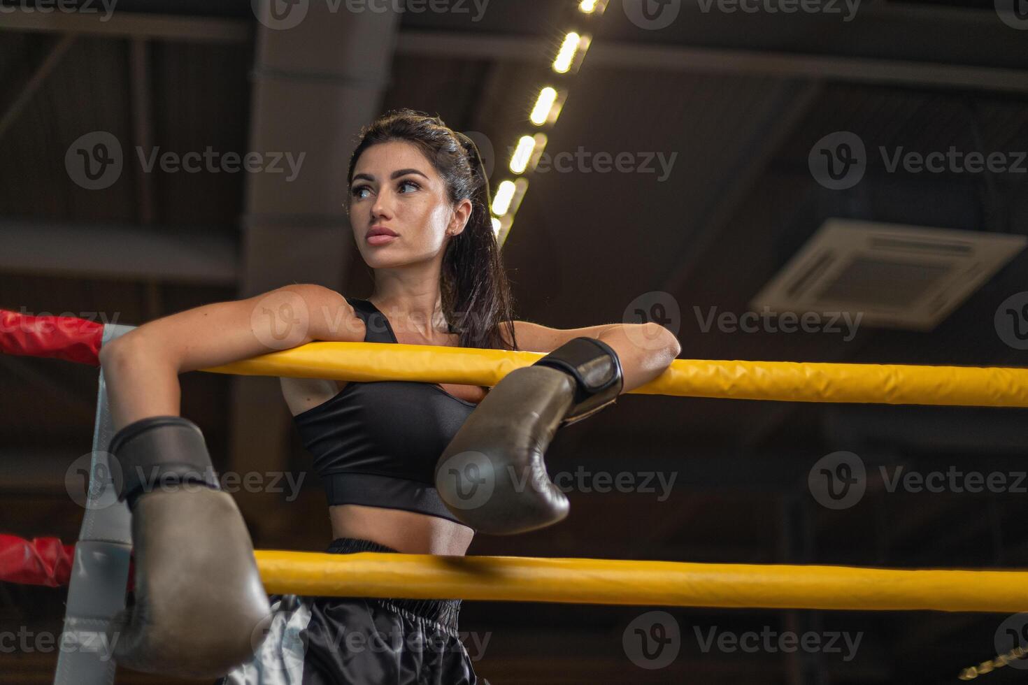 Female boxer resting in ring with focus on determination during training session photo