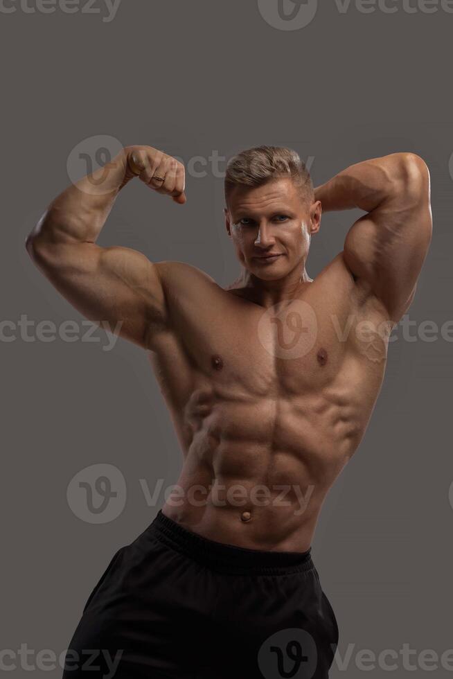 Athlet with a naked torso demonstrates latissimus dorsi and biceps photo