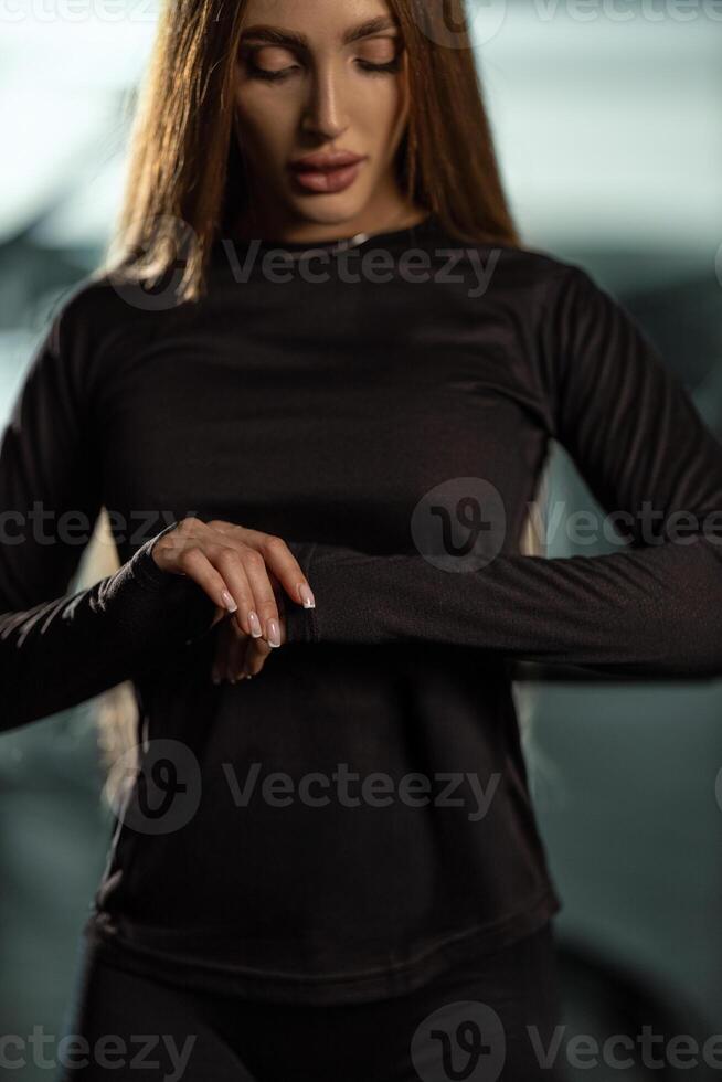 In gym setting woman adjusts her sleeves as she prepares engage in her fitness routine. atmosphere shows focus on health and physical activity photo