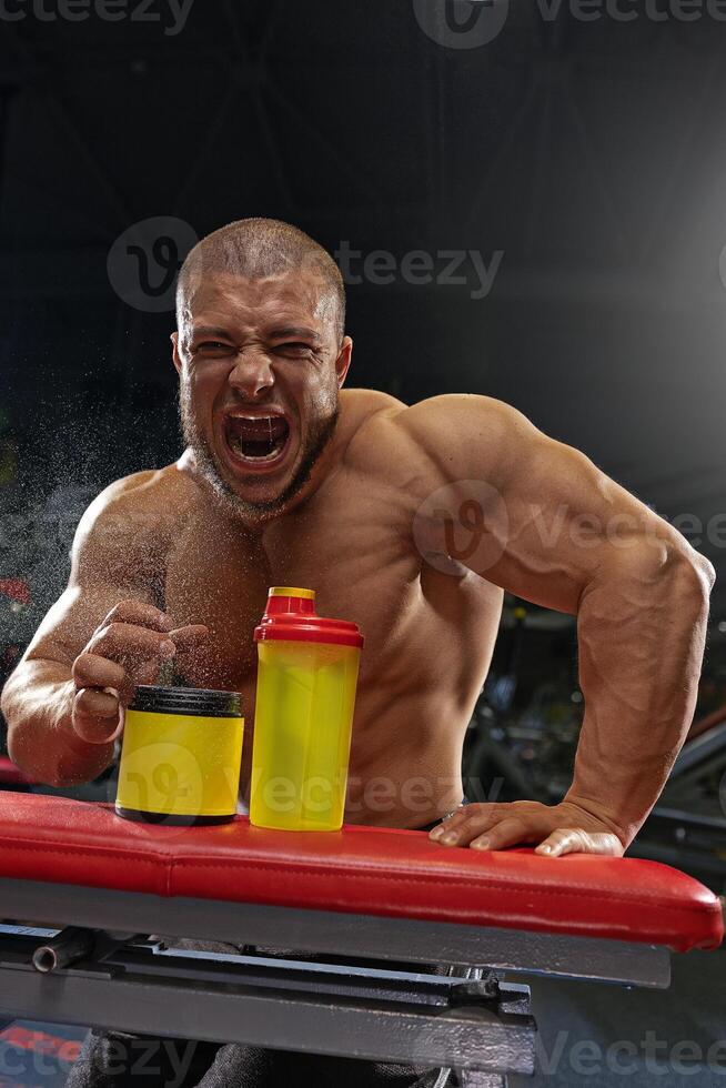 Bodybuilder demonstrating workout intensity and energy during training session in gym at nighttime photo