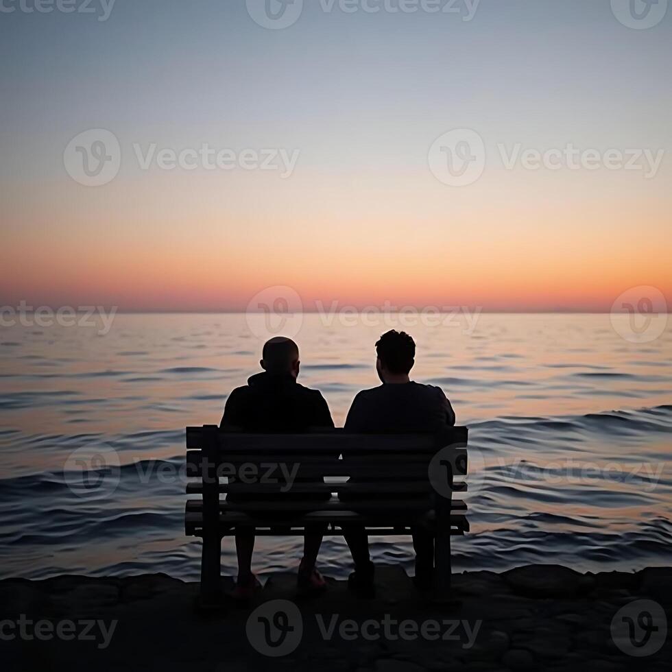 Two Men Sitting on Bench by Ocean at Sunset photo