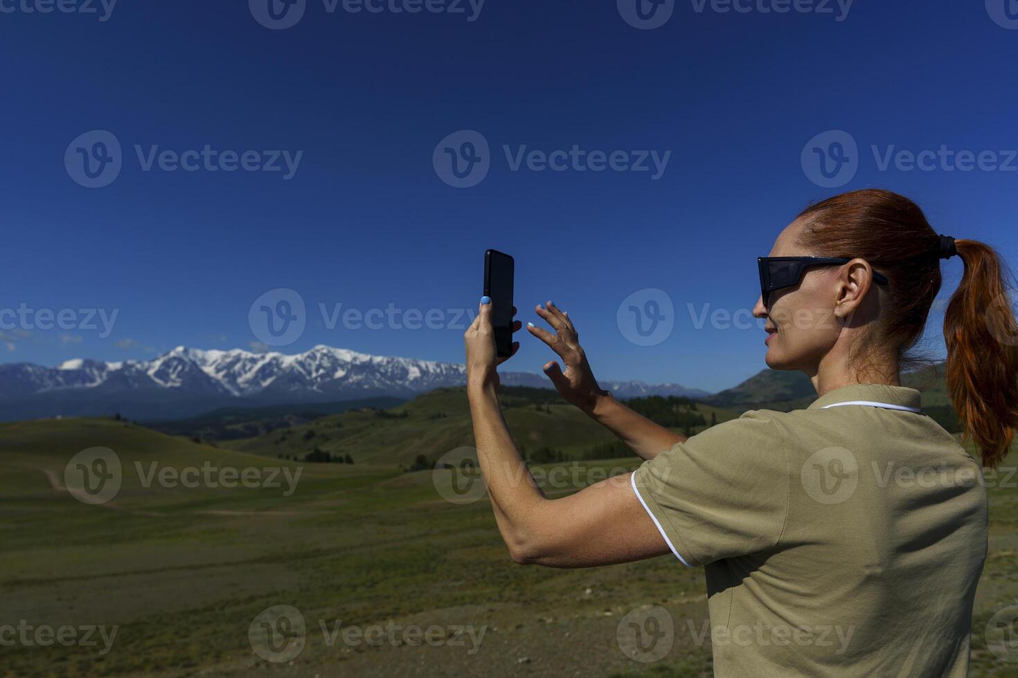 mature woman traveling stopped by the side of the road and takes pictures of the mountains photo