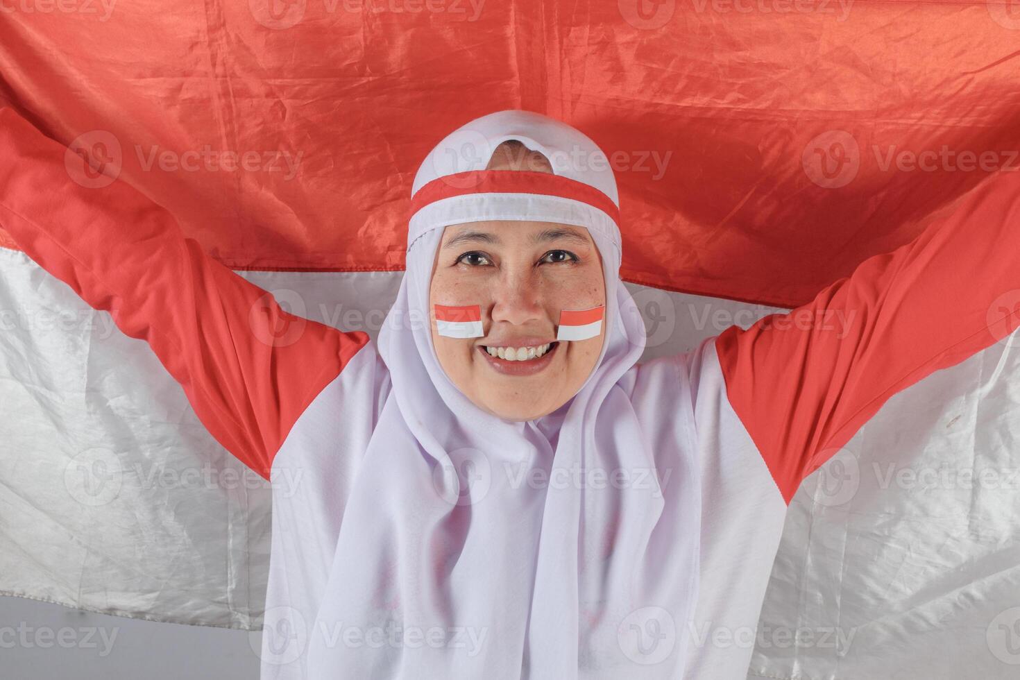 Smiling Indonesian woman raises national flag with joyful patriotic expression photo