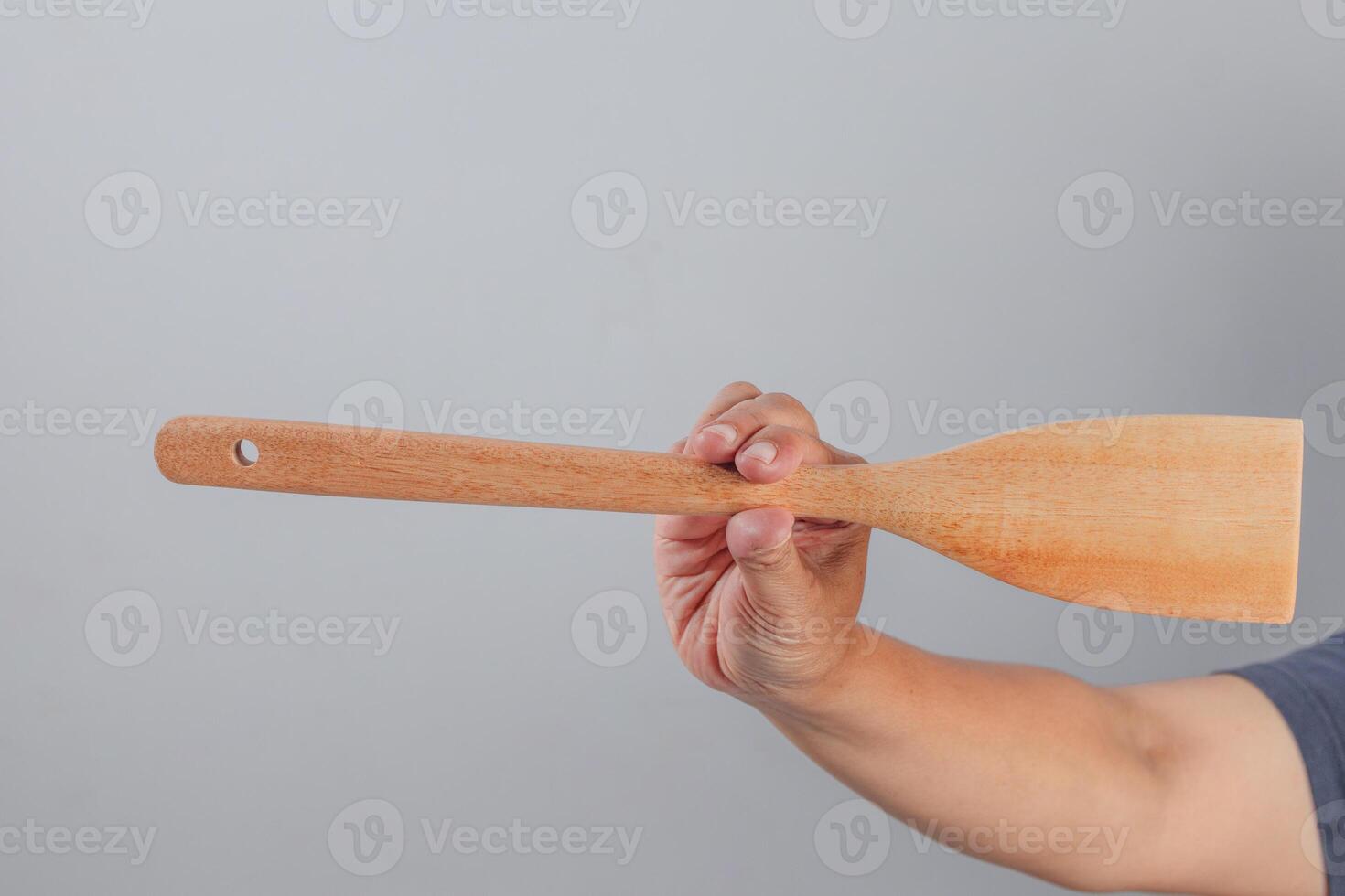 Hand holding long wooden spatula horizontally for cooking utensil concept photo