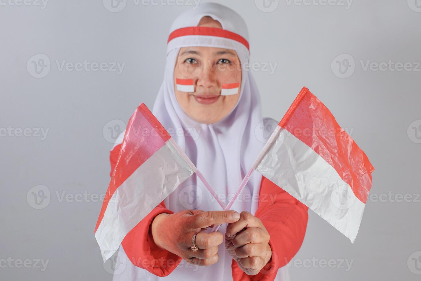 Muslim woman proudly showing two small flags during independence celebration with strong patriotic expression photo
