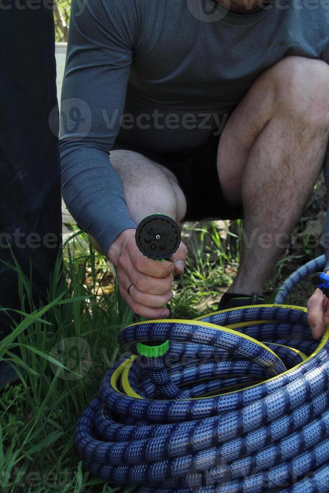 Male hand holding a watering hose photo