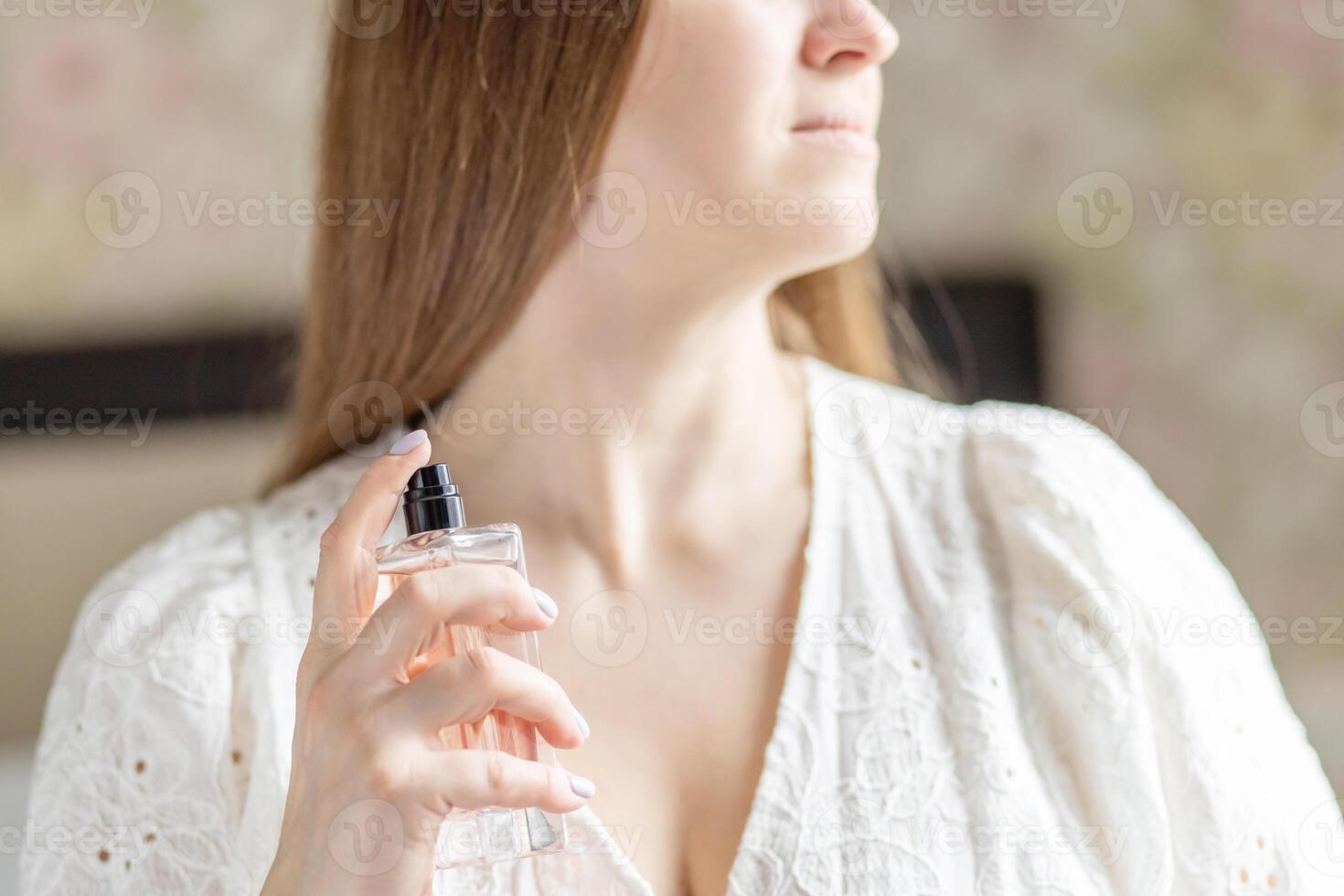 Beautiful young woman with bottle of perfume at home, closeup photo