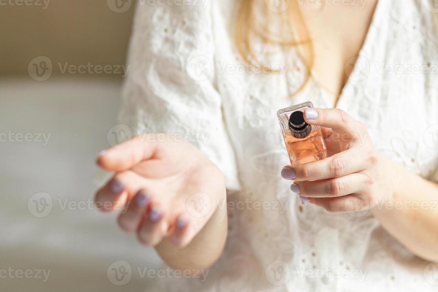 Beautiful young woman using perfume at home photo