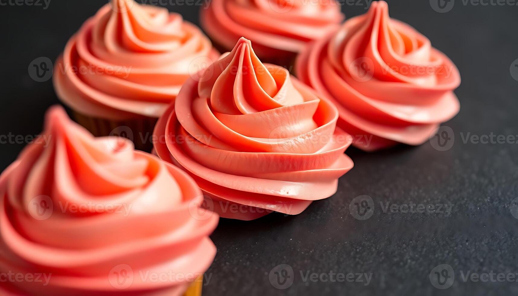 cupcakes with pink frosting on a black surface photo