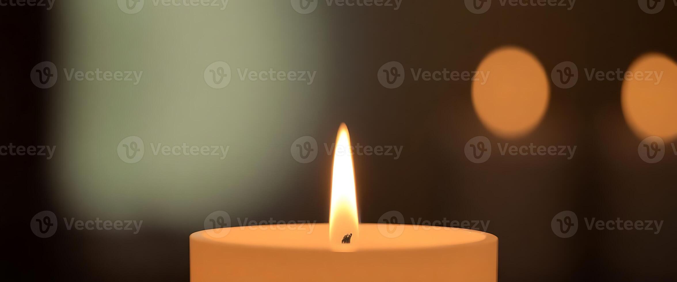 A candle is lit in front of a dark background photo