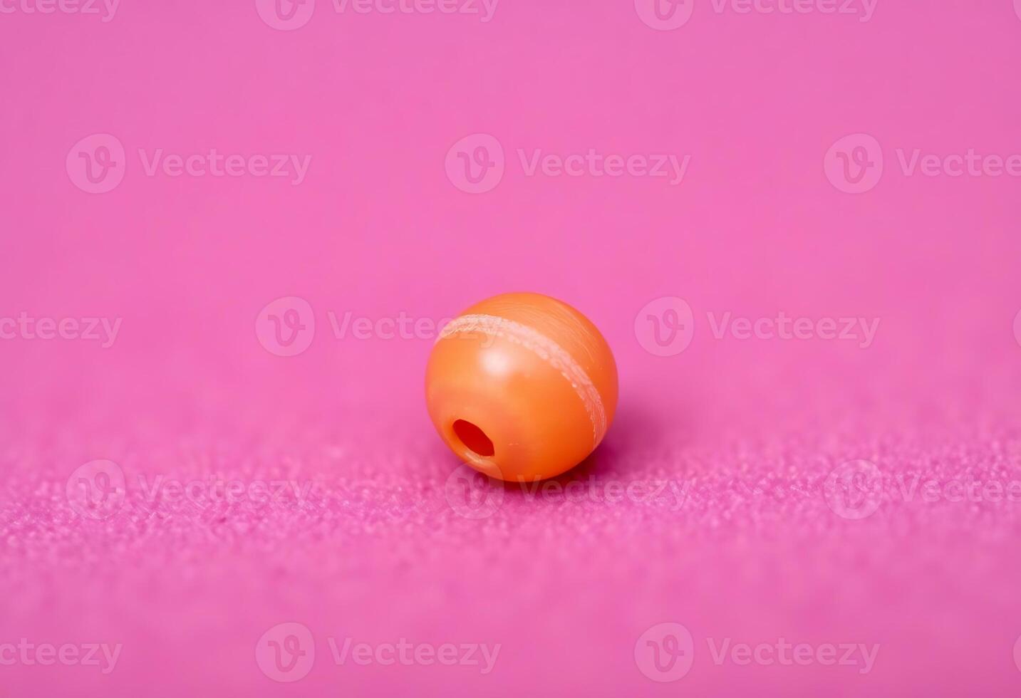 small orange object on a pink surface photo
