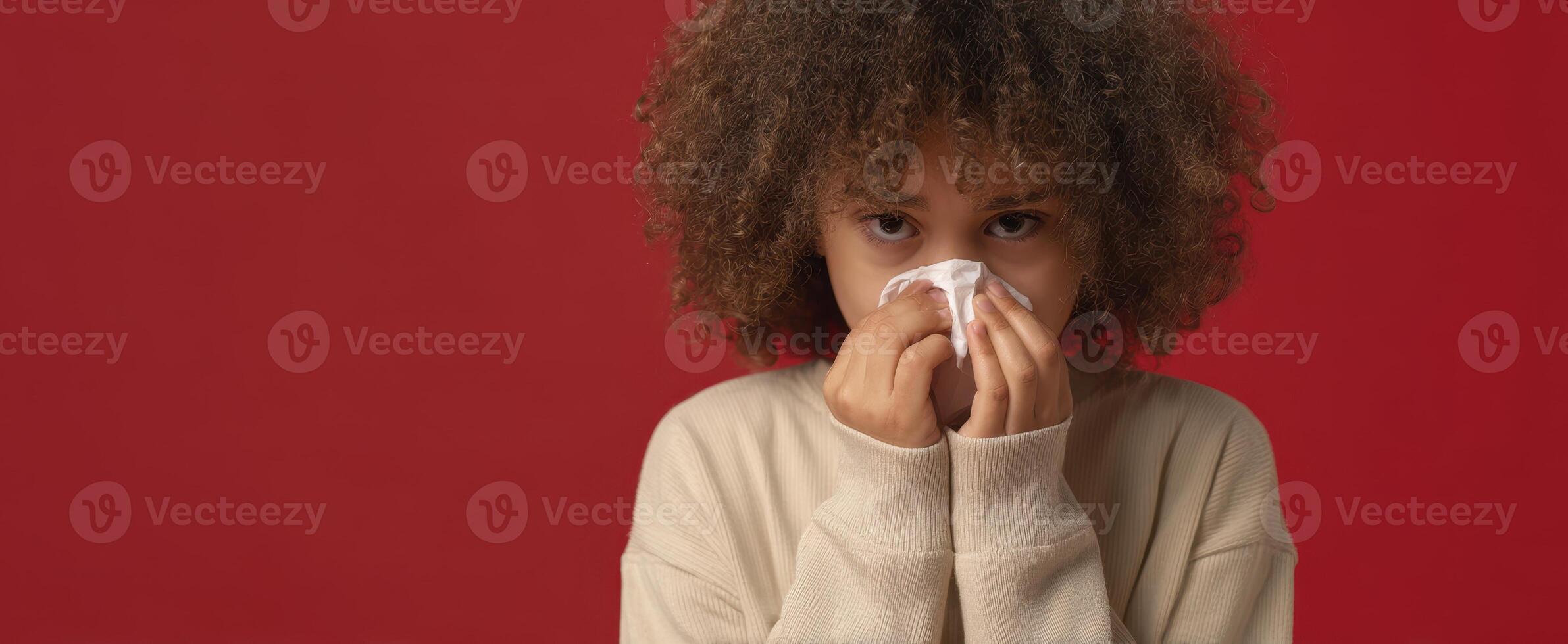 The girl with a tissue expressing discomfort and sadness against a red background. photo