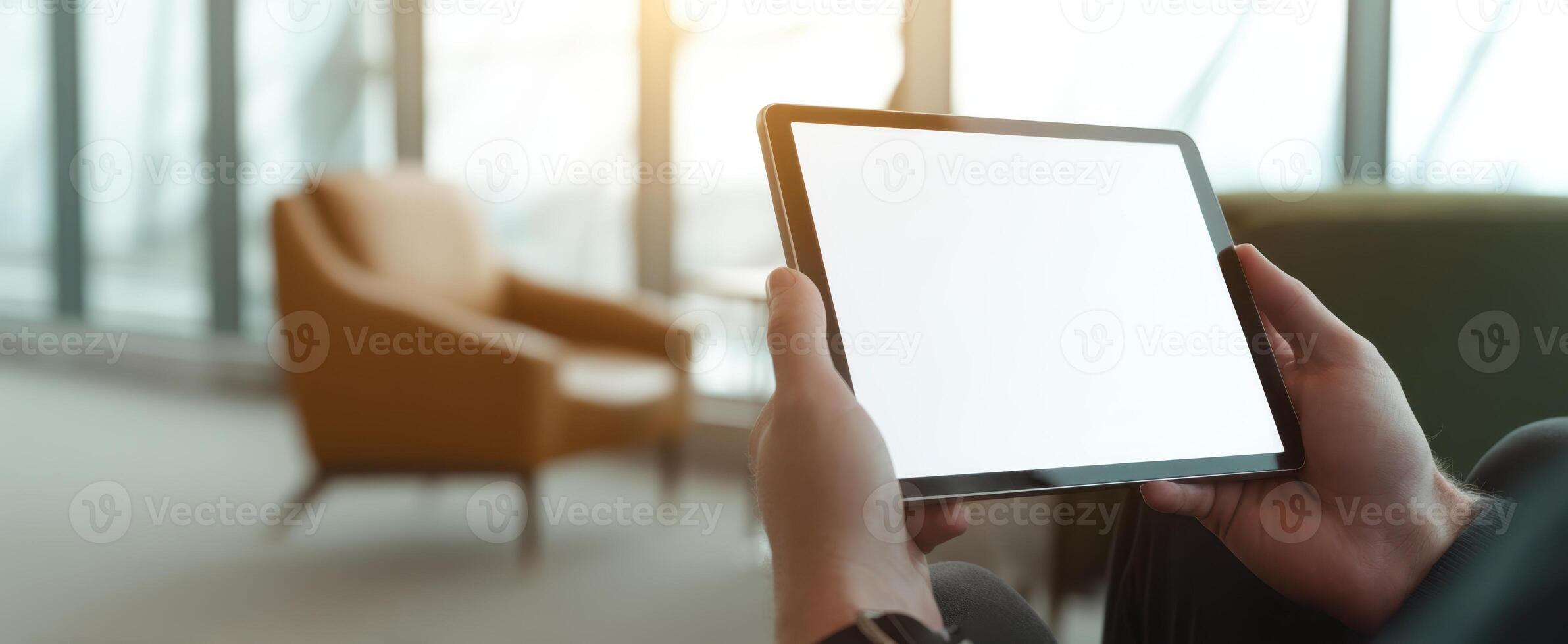 The tablet held in hands against a stylish indoor backdrop with bright lighting. photo