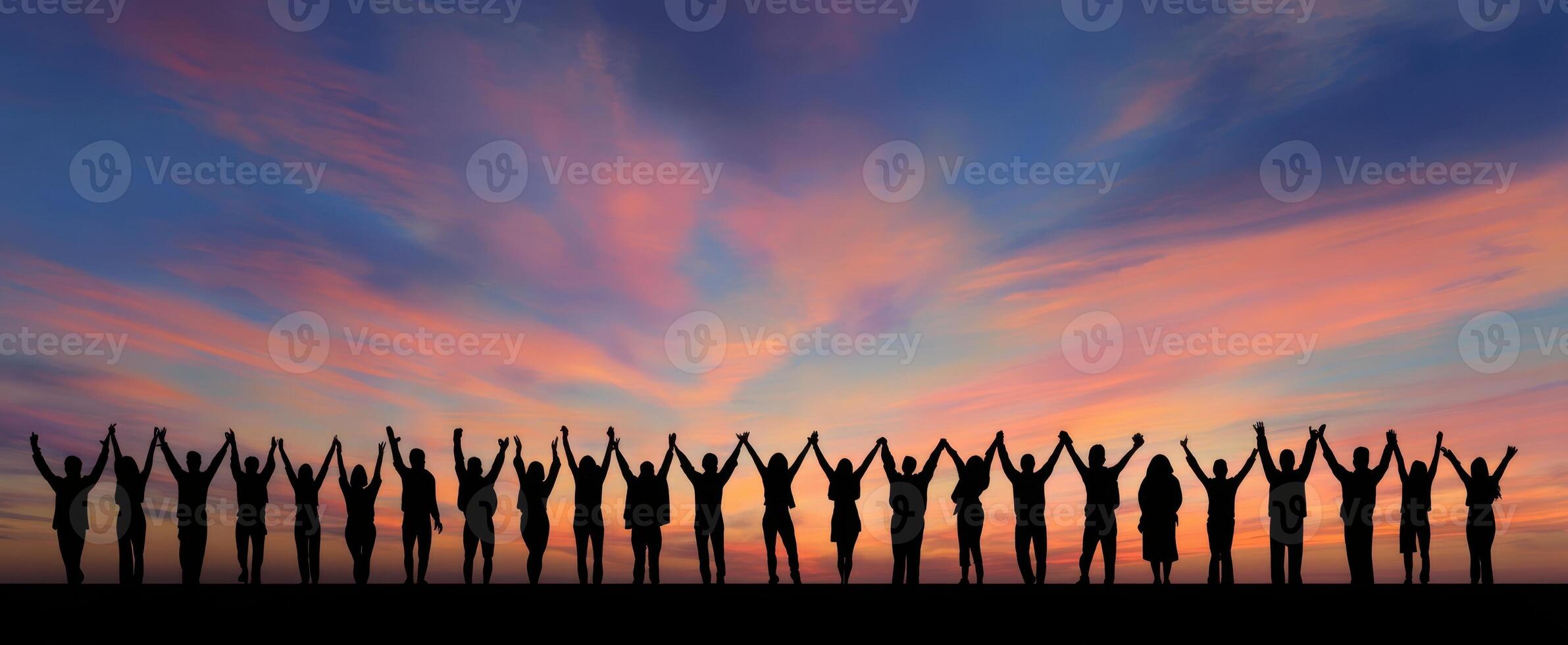 The silhouette of a vibrant group celebrating joy under a colorful sunset sky. photo