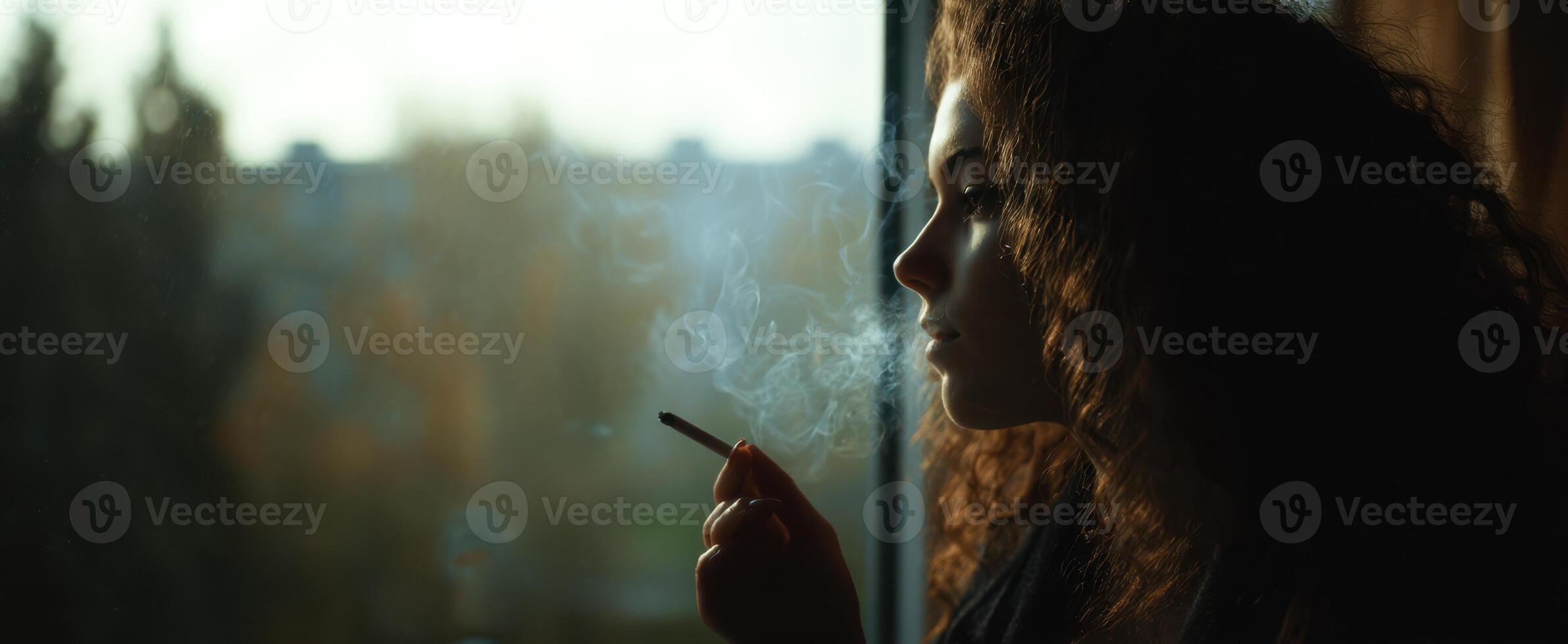 The woman gazing thoughtfully out of the window while smoking. photo