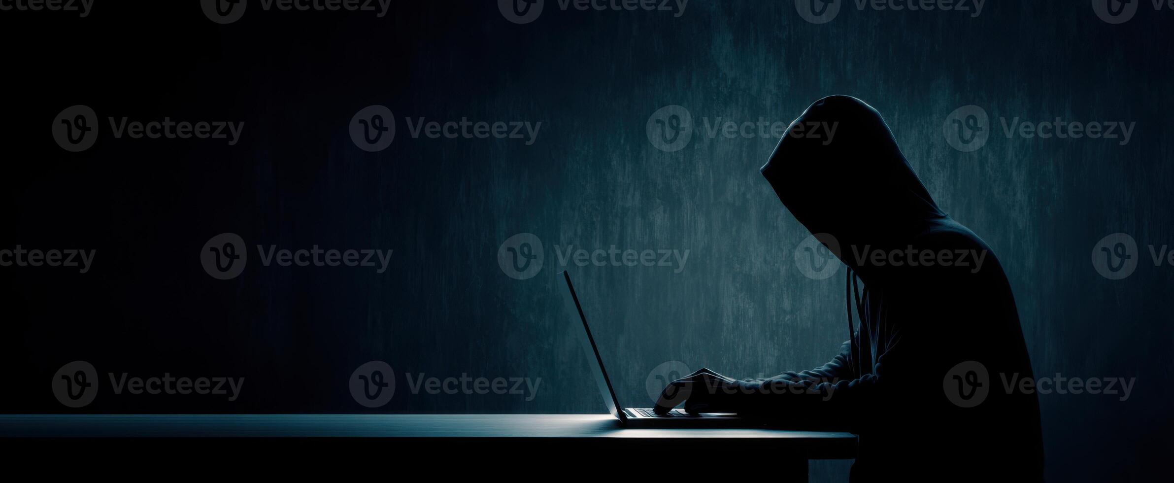 The mysterious hacker working in the shadows on a laptop. photo