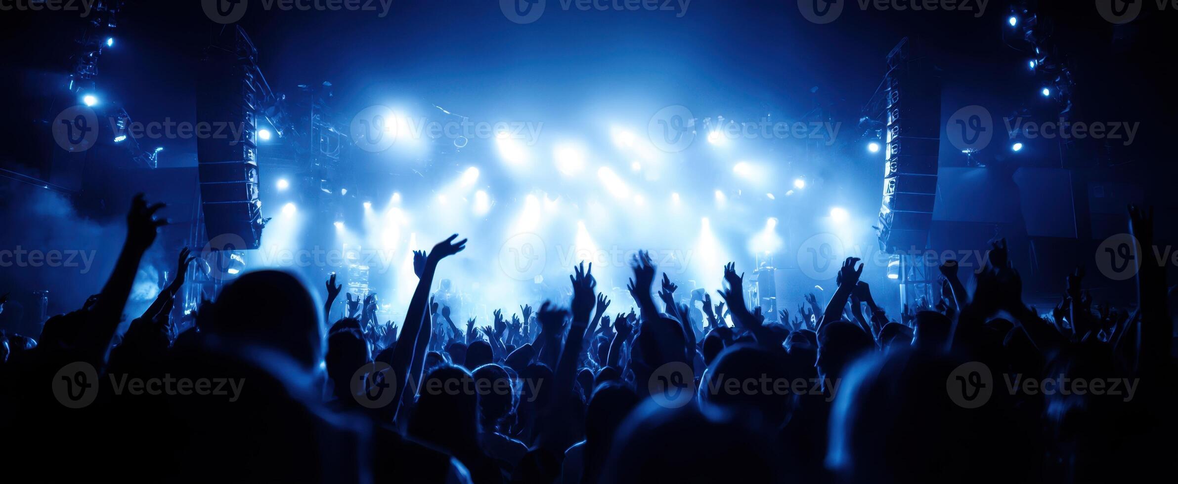 The vibrant crowd celebrating an electrifying live concert experience with blue lighting. photo