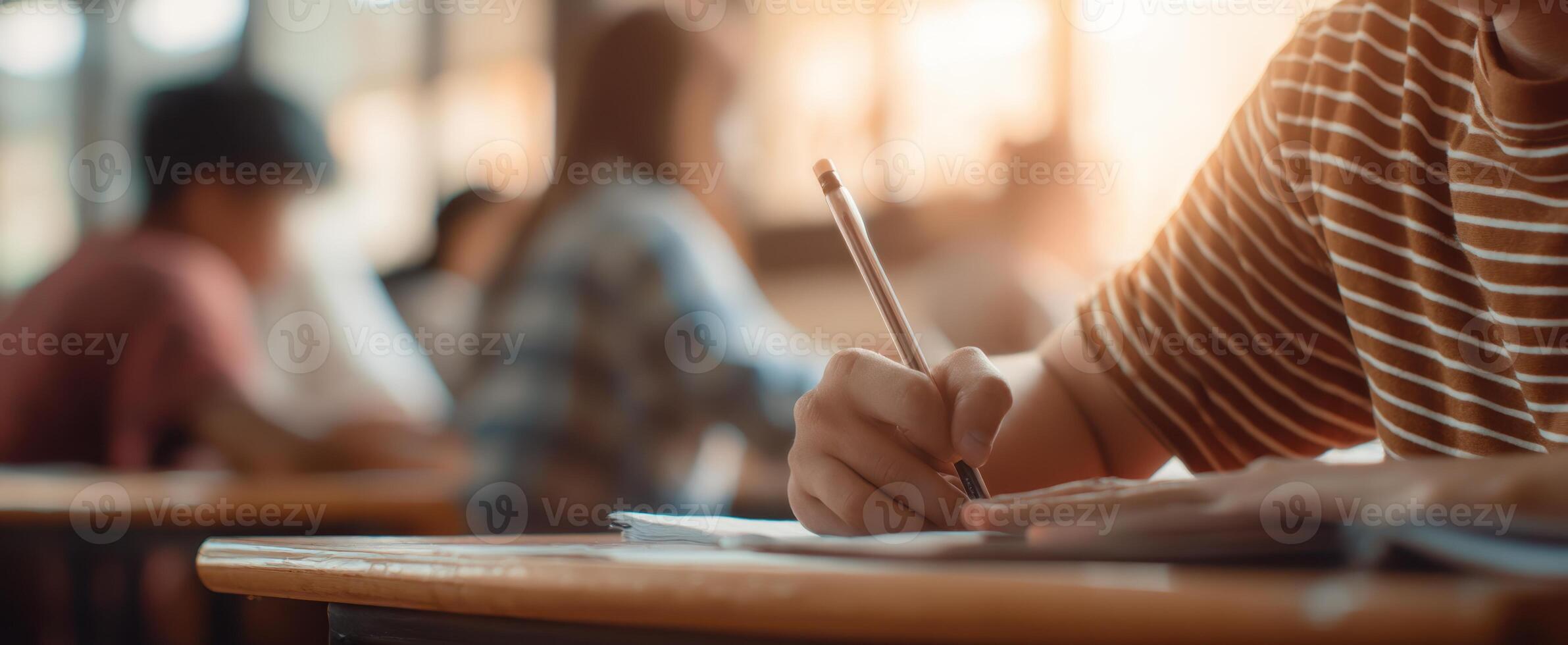 The student writing notes in a classroom during a study session. photo
