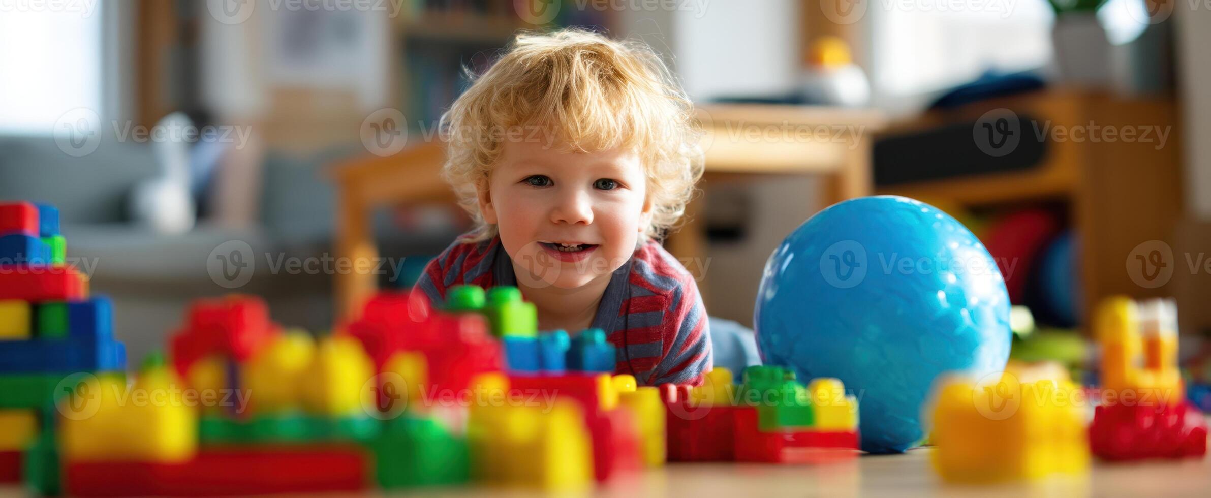 The cheerful toddler playing with colorful building blocks and a blue ball. photo