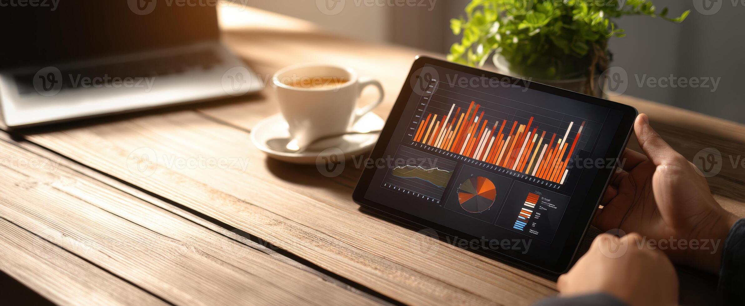 The tablet displaying colorful graphs and charts on a wooden workspace. photo