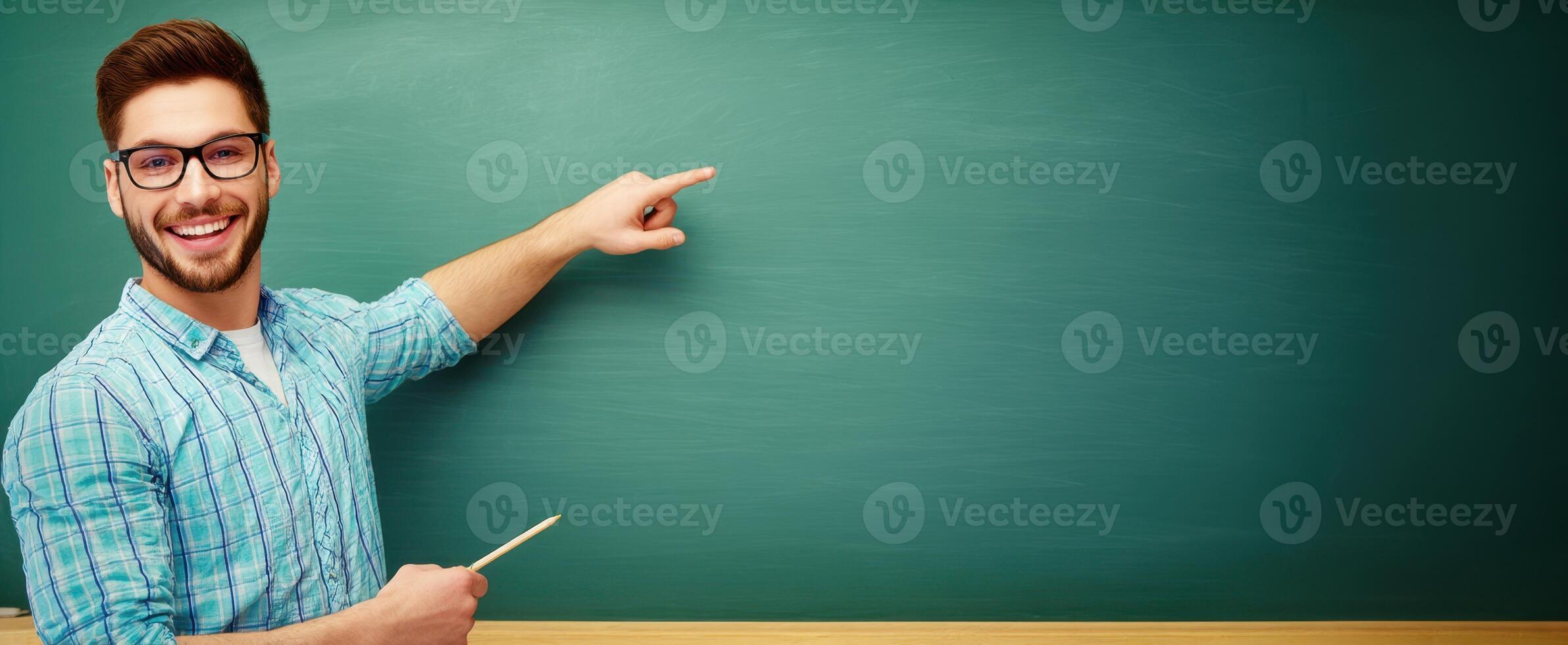 The enthusiastic teacher pointing at a blank chalkboard in a classroom. photo