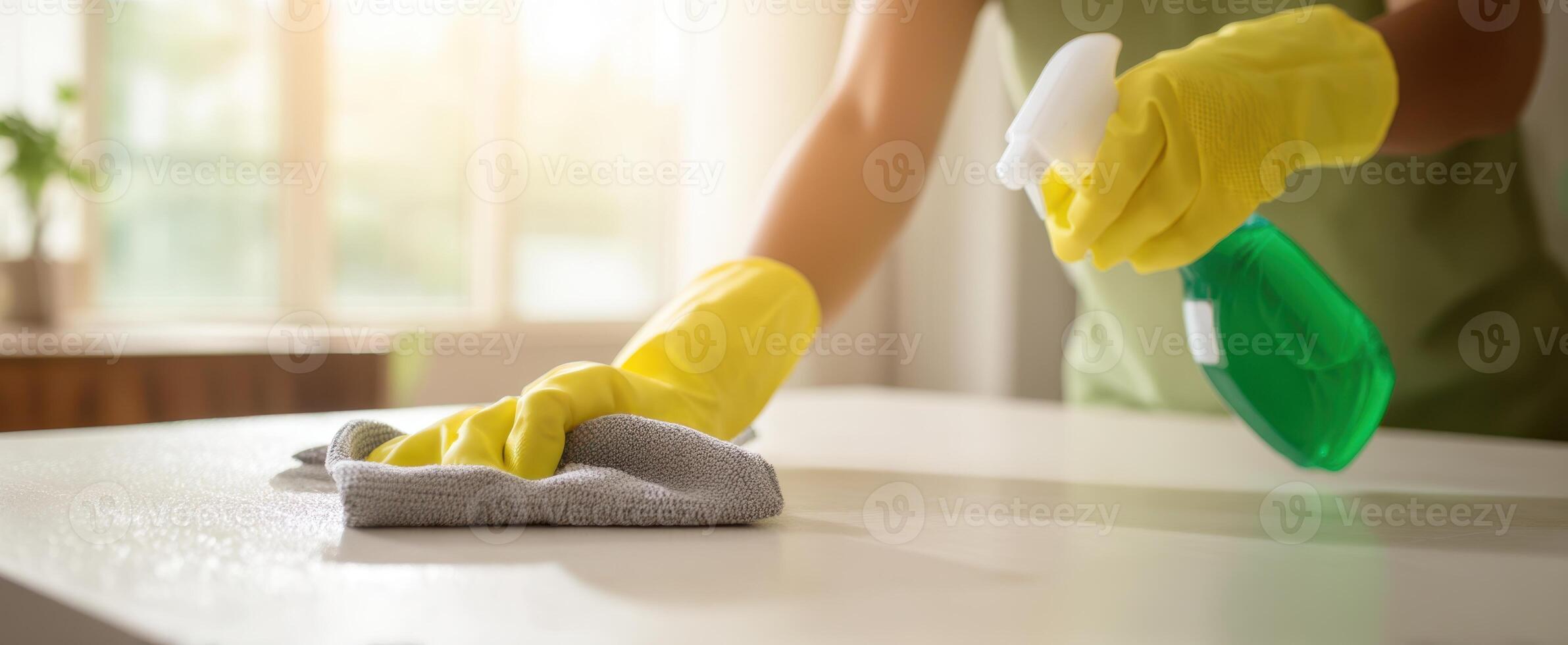 The person cleaning a countertop with spray and cloth in a bright home environment. photo