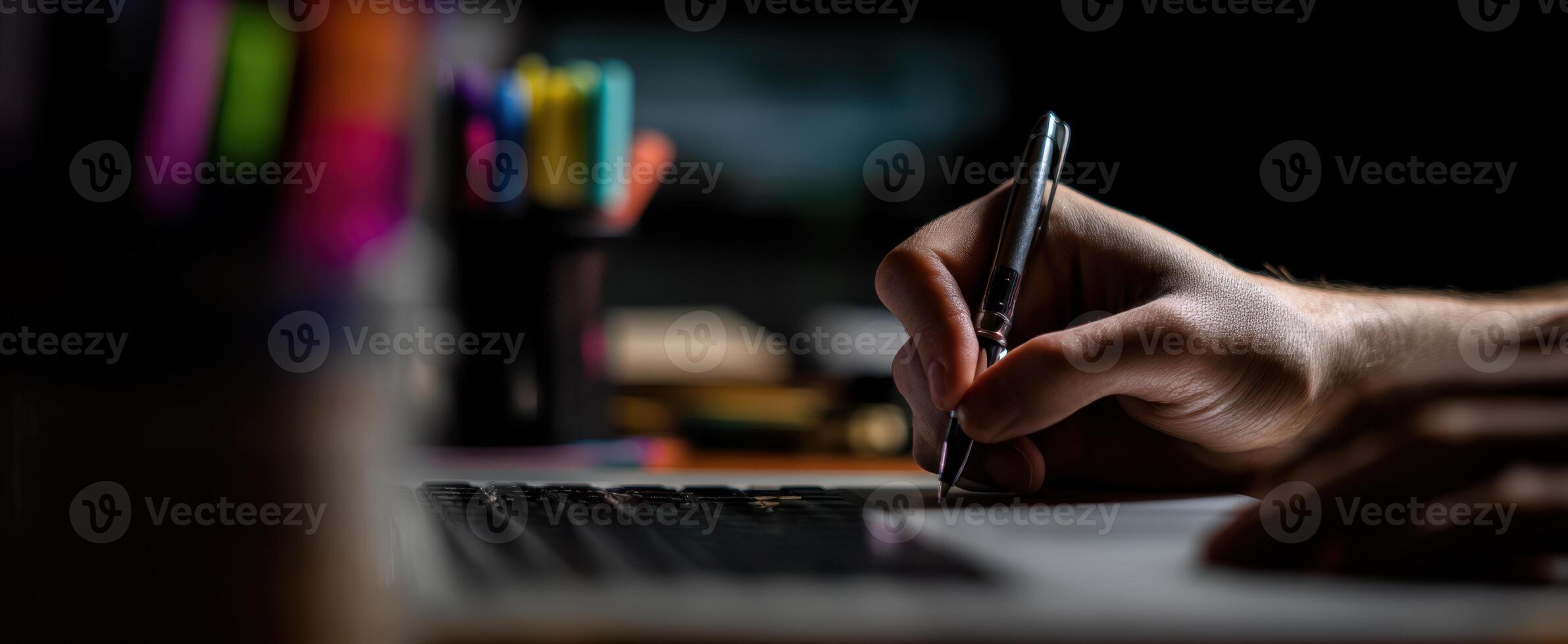 The hand writing on a notepad next to a laptop in a creative workspace. photo