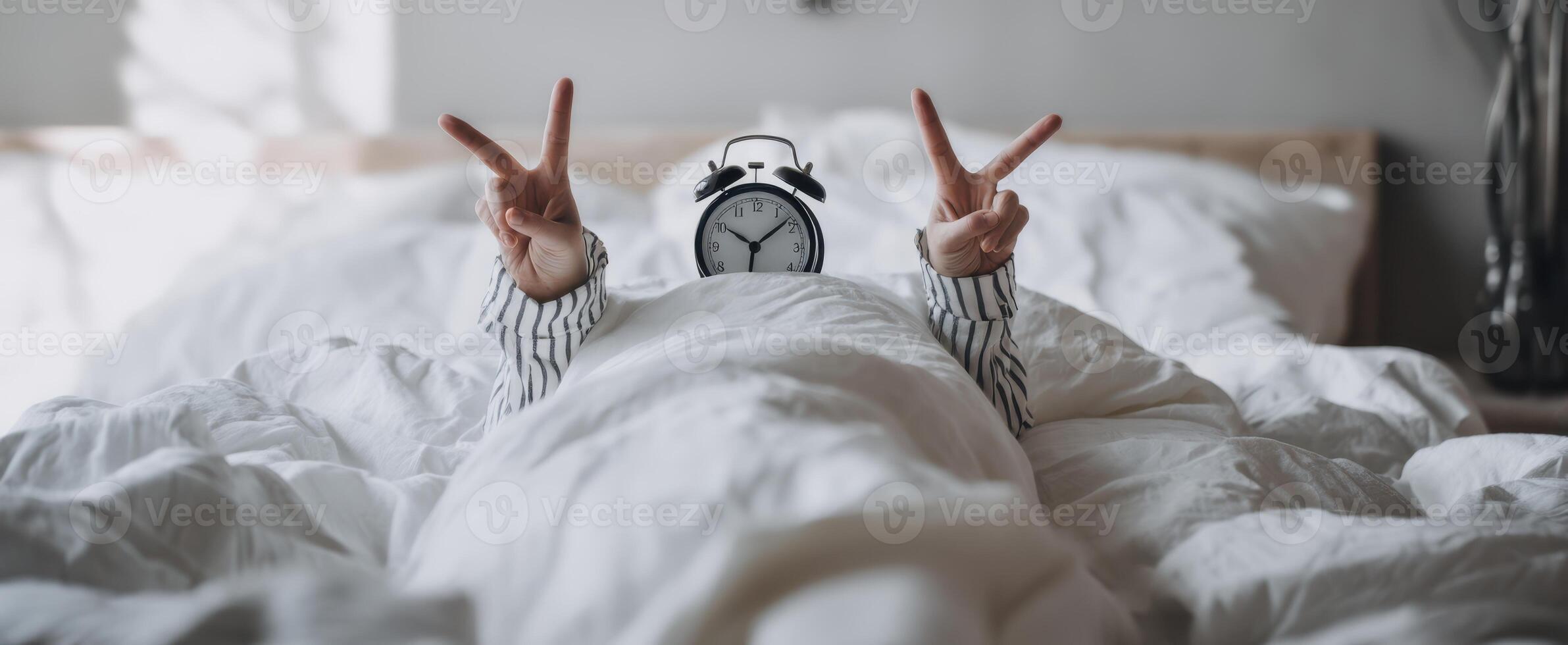 The playful person wearing an alarm clock celebrating happiness in bed. photo