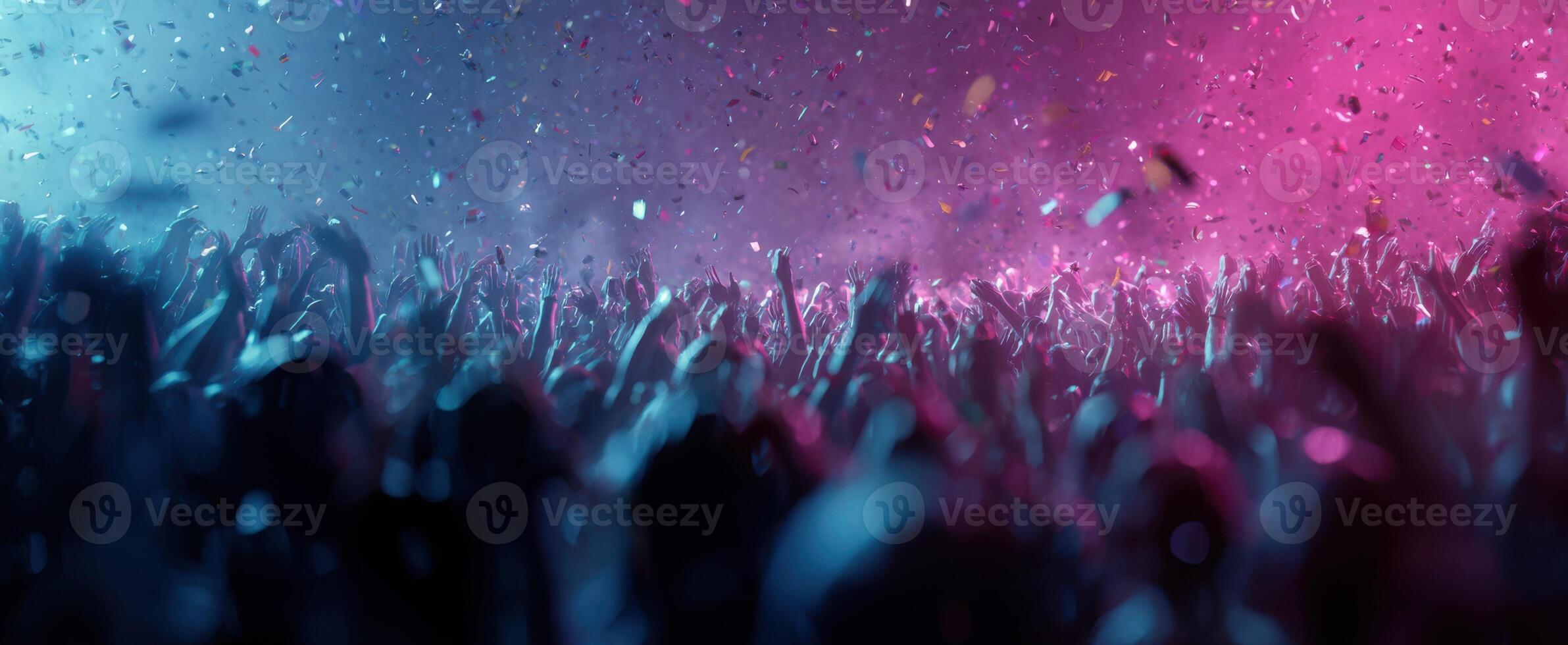 The lively crowd celebrating at a vibrant concert with colorful confetti. photo