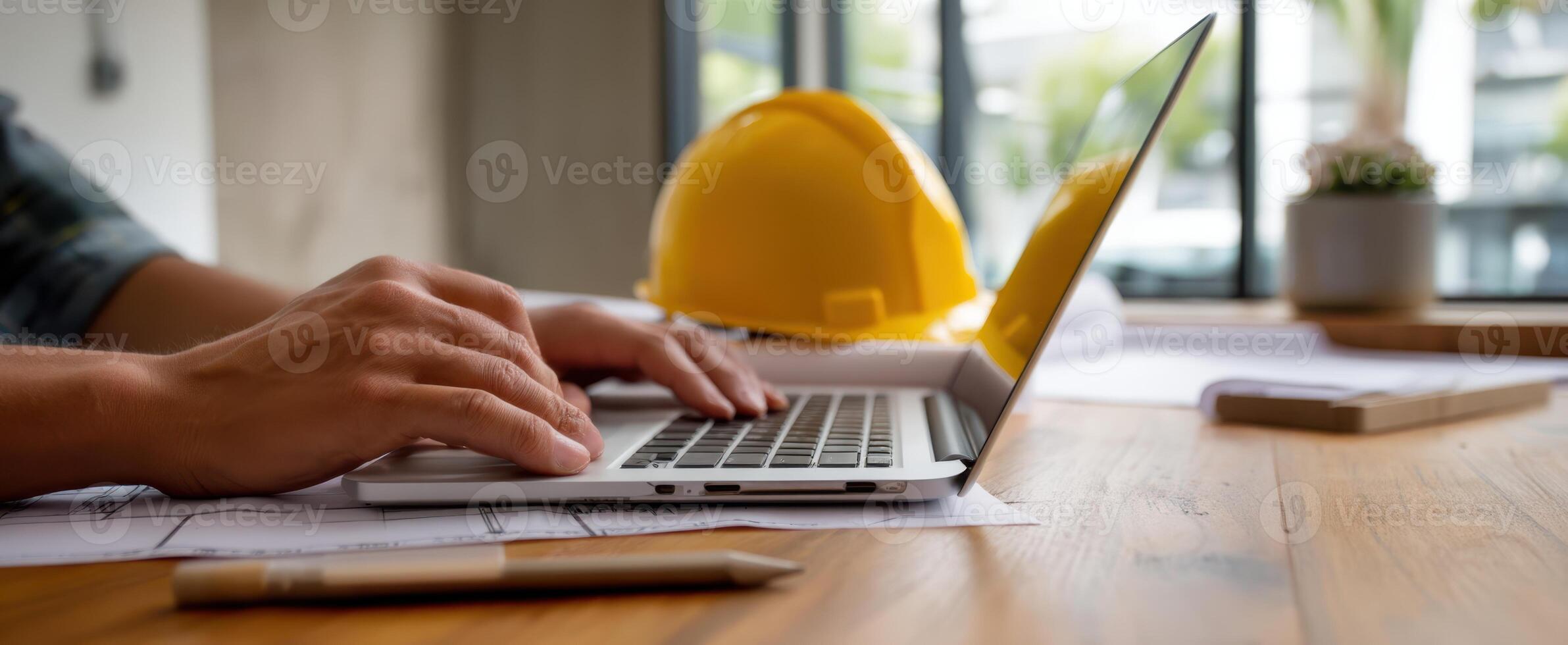 The laptop on a construction desk with a hardhat nearby, symbolizing work. photo