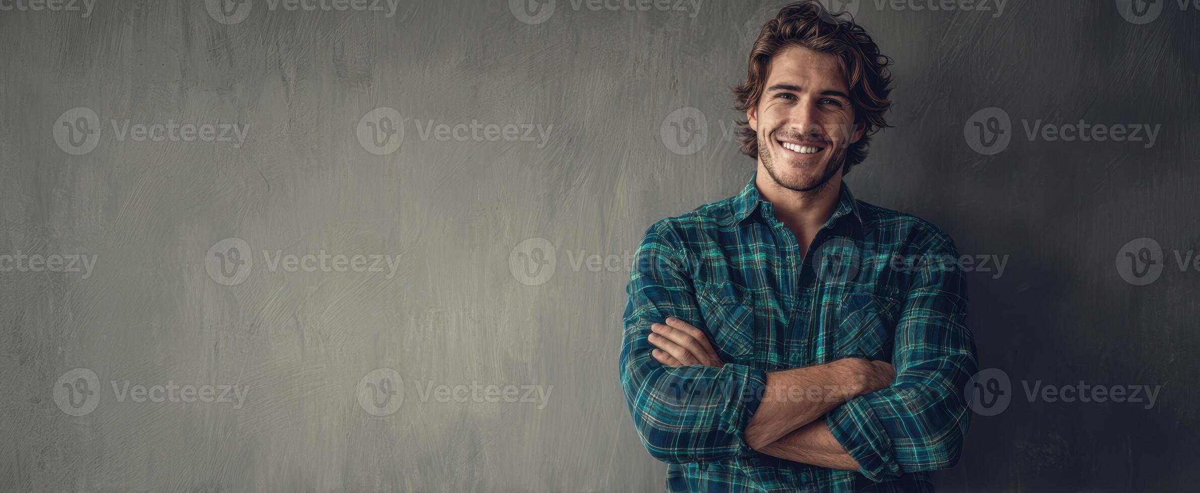 The smiling man in a plaid shirt against a textured backdrop. photo