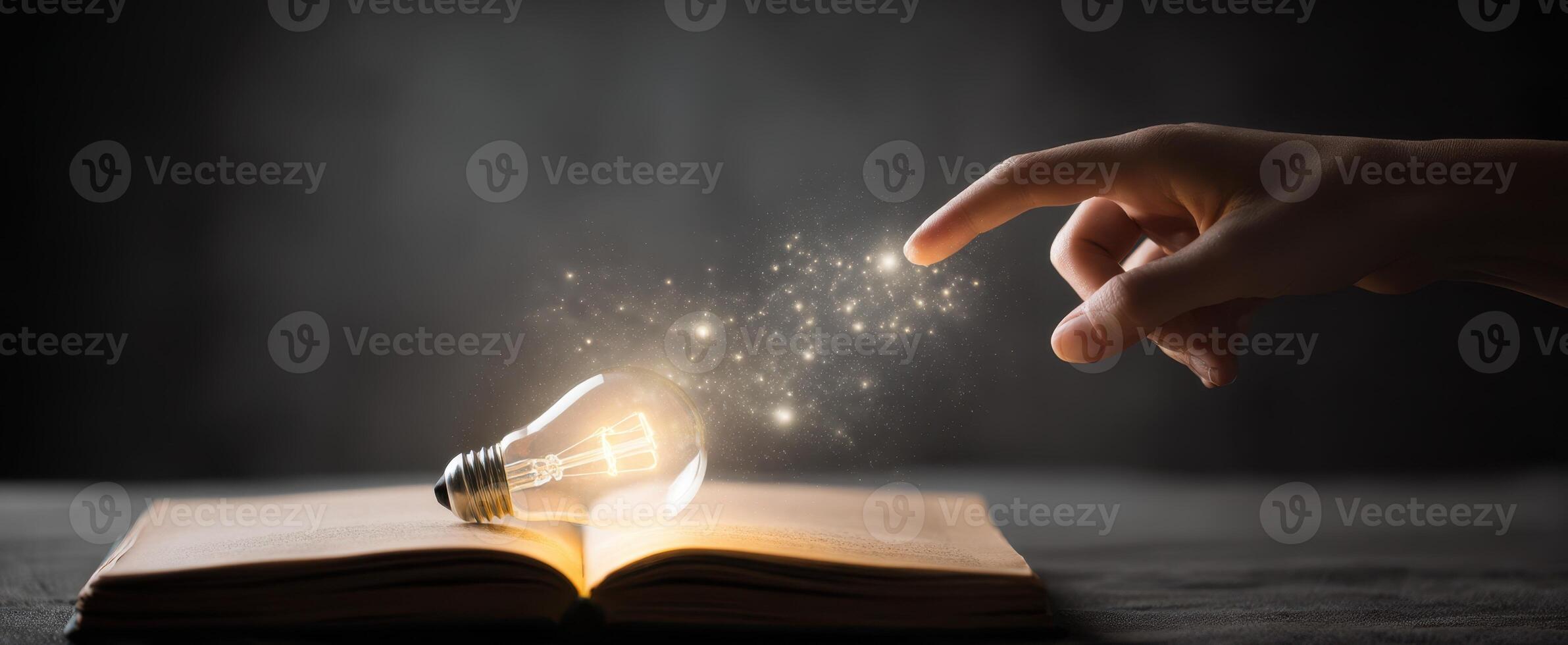 The hand igniting creativity with a magical lightbulb above an open book. photo